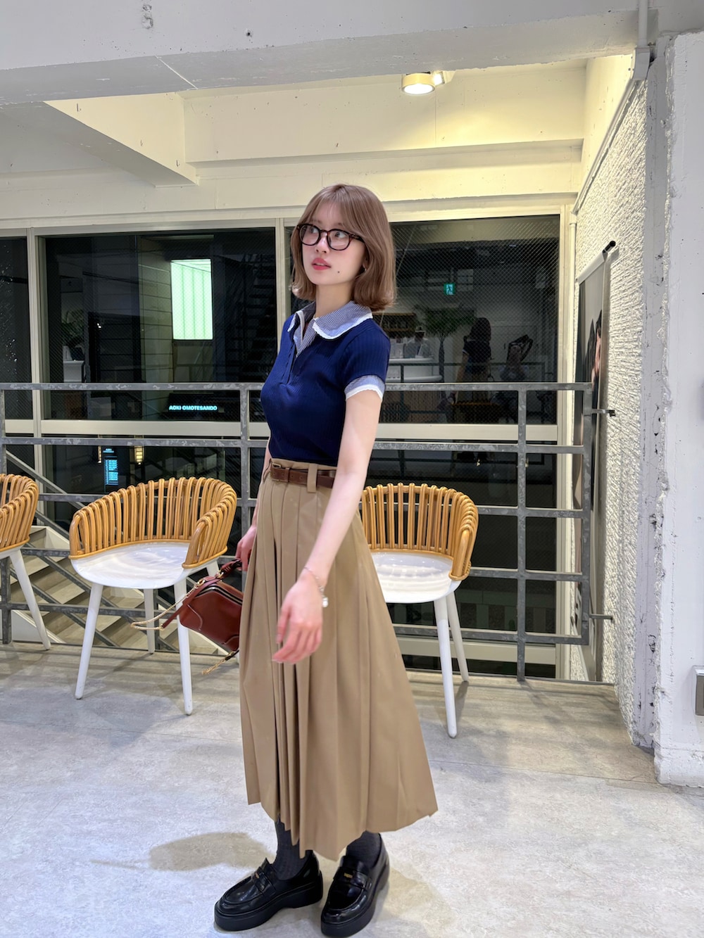ブラウン系のショルダーバッグ、ベージュ系のスカート、ブルー系のトップスを着用したレディースの春コーディネートの3枚目の写真