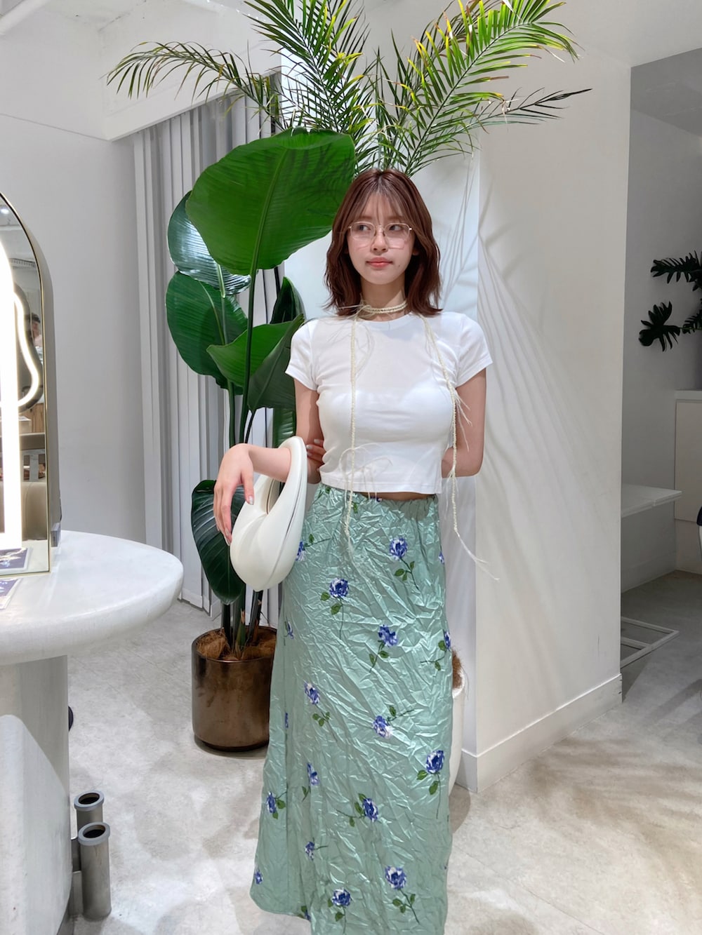 グリーン系のスカート、ホワイト系のハンドバッグ、ホワイト系のTシャツ/カットソーを着用したレディースの夏コーディネートの2枚目の写真