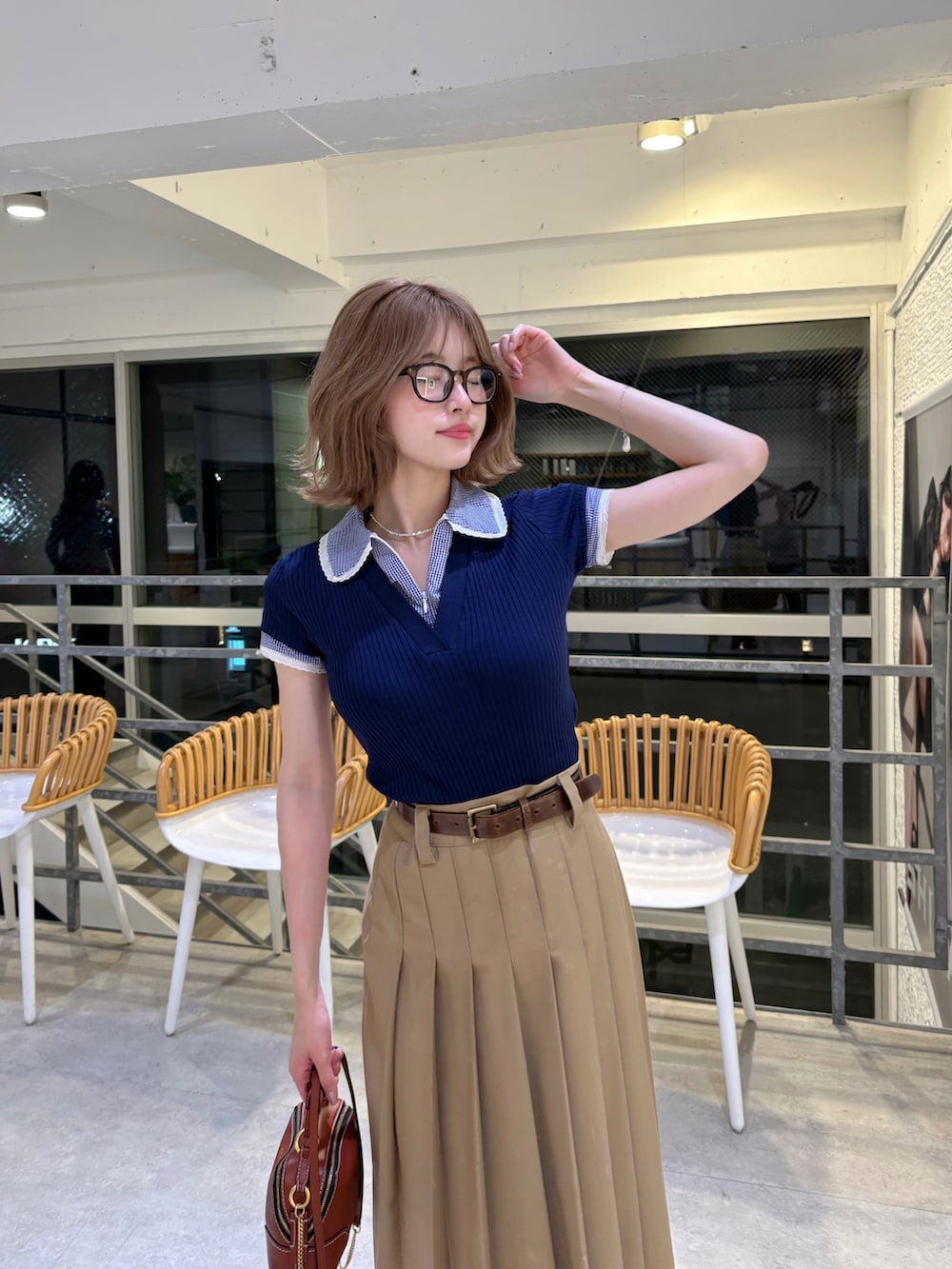 ブラウン系のショルダーバッグ、ベージュ系のスカート、ブルー系のトップスを着用したレディースの春コーディネートの2枚目の写真