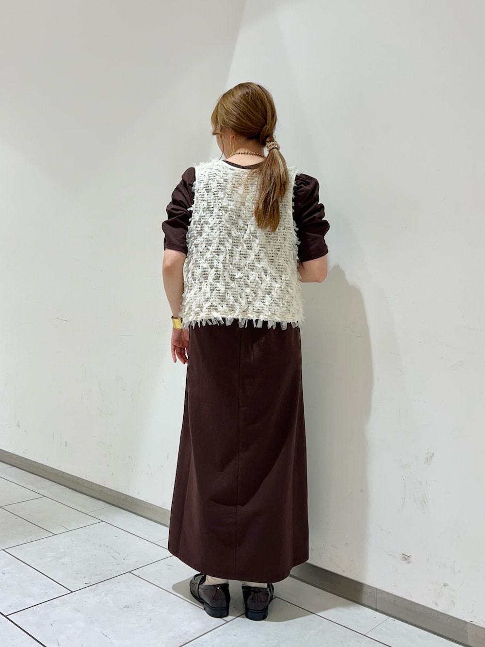 ホワイト系のベスト、ブラウン系のワンピース、ブラウン系のローファーを着用したレディースの夏コーディネートの3枚目の写真