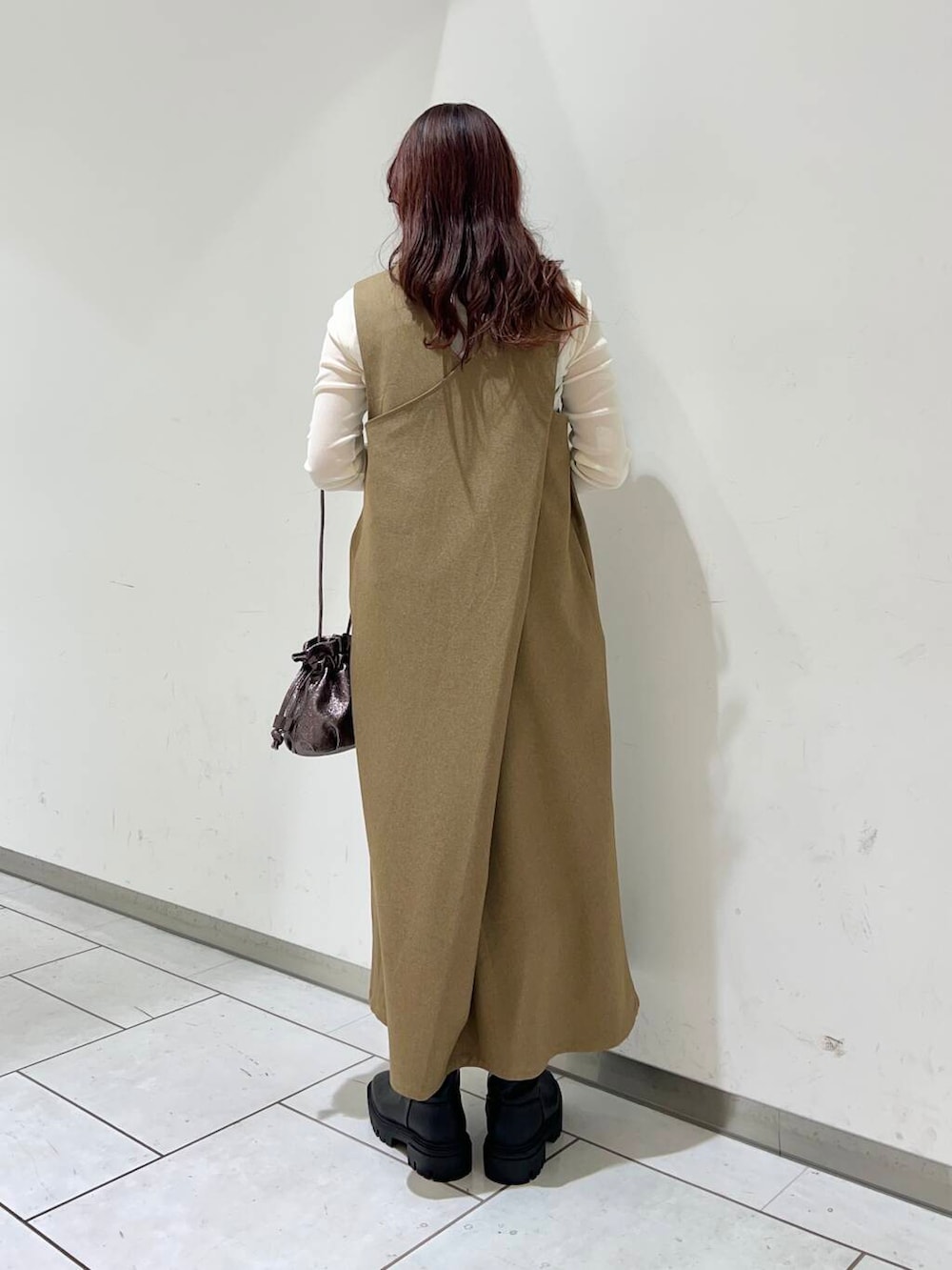 ブラック系のブーツ、ホワイト系のTシャツ/カットソー、シルバー系のショルダーバッグを着用したレディースの冬コーディネートの2枚目の写真