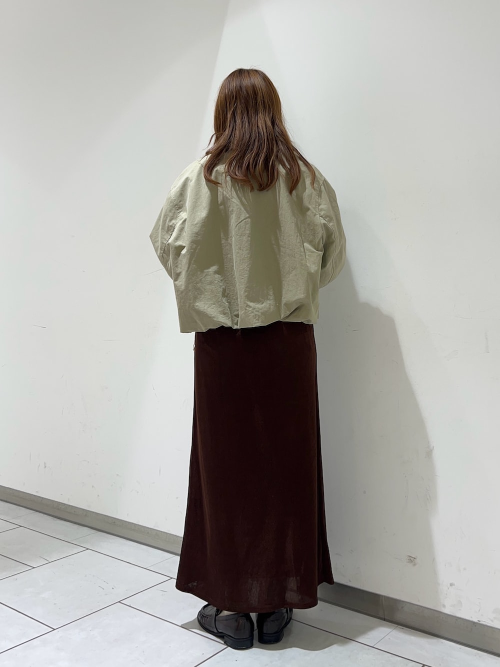 ブラウン系のスカート、ホワイト系のTシャツ/カットソー、ベージュ系のブルゾンを着用したレディースの冬コーディネートの3枚目の写真