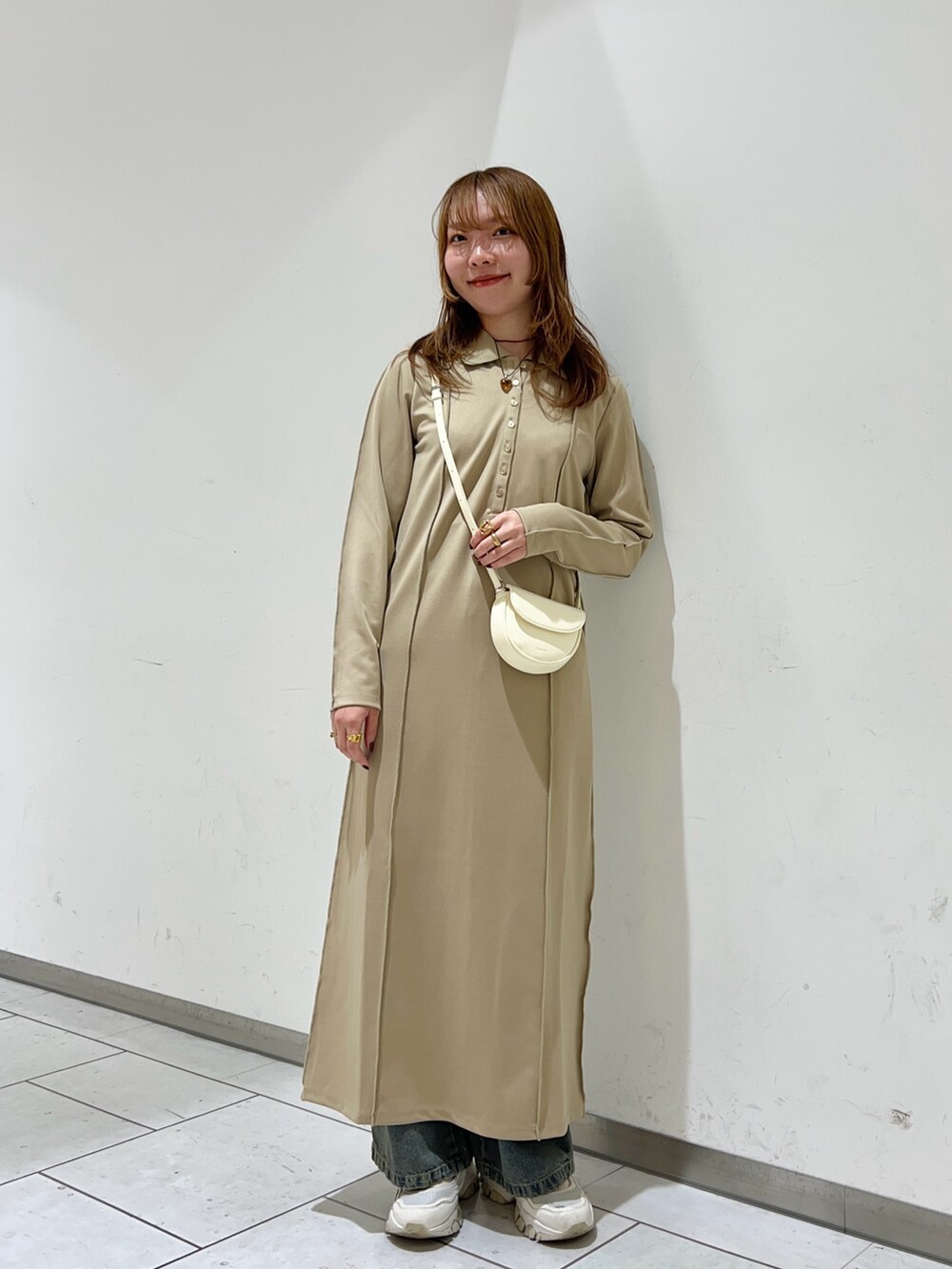 パープル系のワンピース、ブルー系のデニムパンツ、ホワイト系のショルダーバッグを着用したレディースの冬コーディネートの2枚目の写真