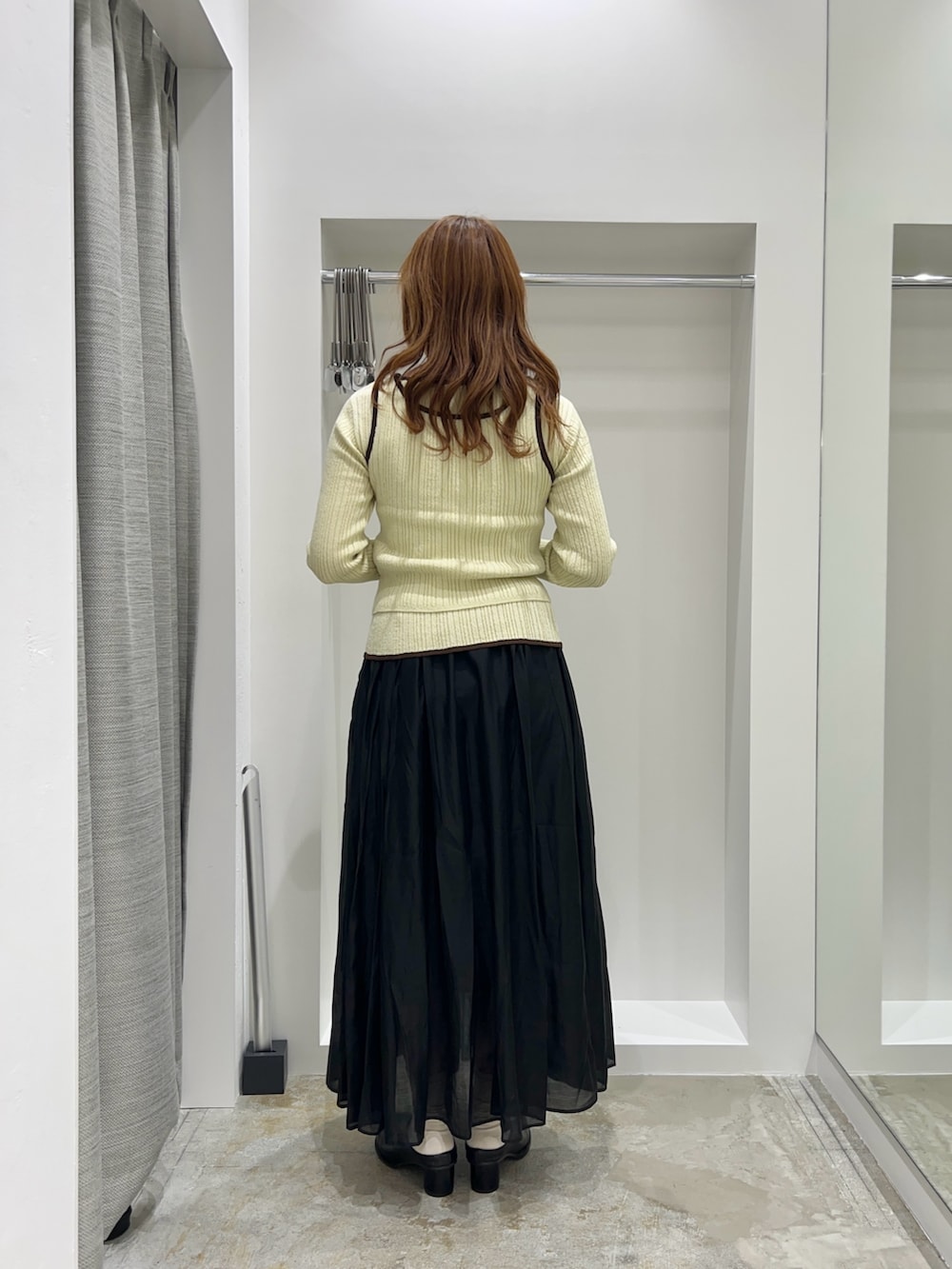 グリーン系のニット/セーター、ブラック系のスカート、ブラック系のサンダルを着用したレディースの春コーディネートの3枚目の写真