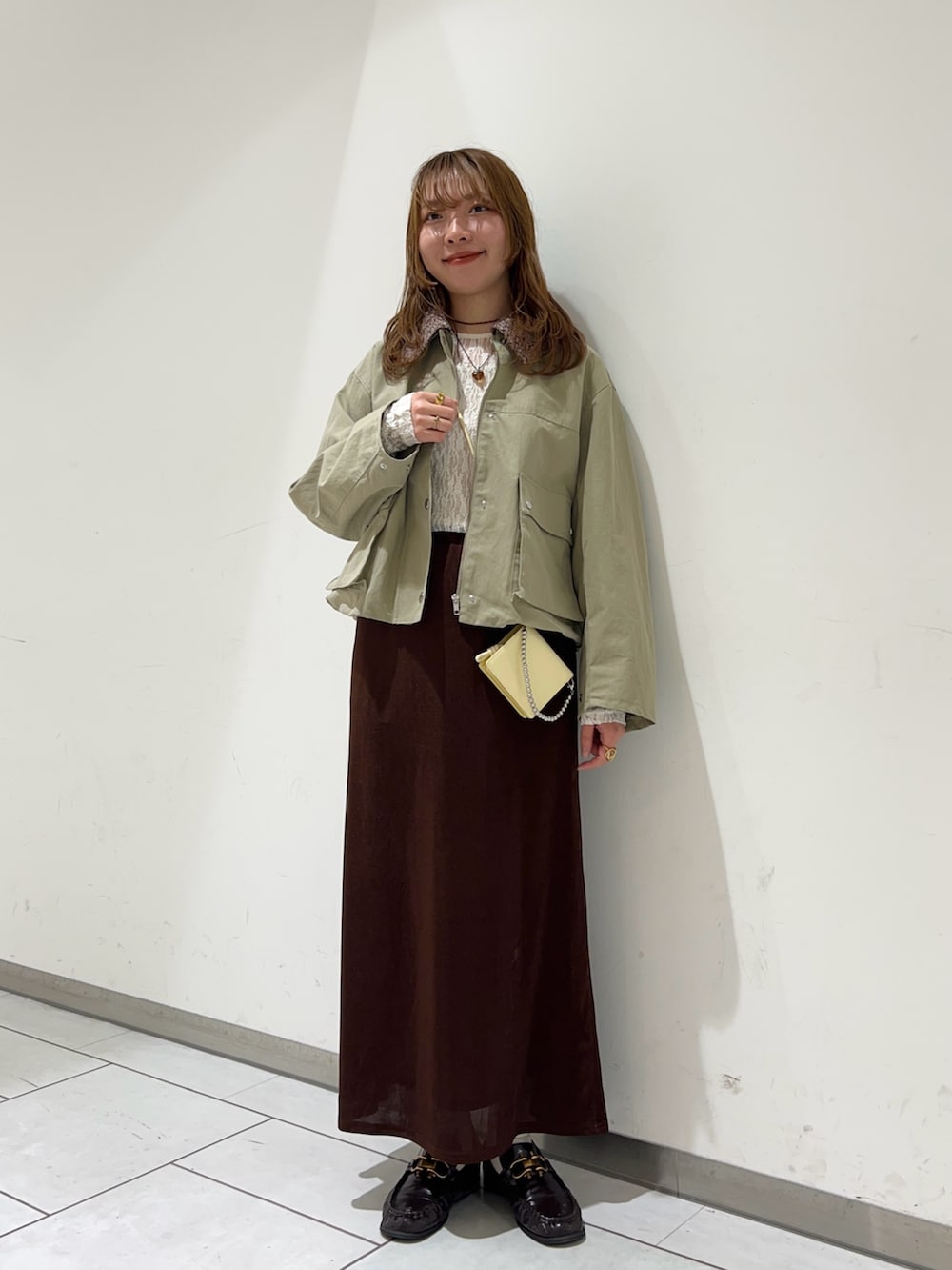 ブラウン系のスカート、ホワイト系のTシャツ/カットソー、ベージュ系のブルゾンを着用したレディースの冬コーディネートの2枚目の写真