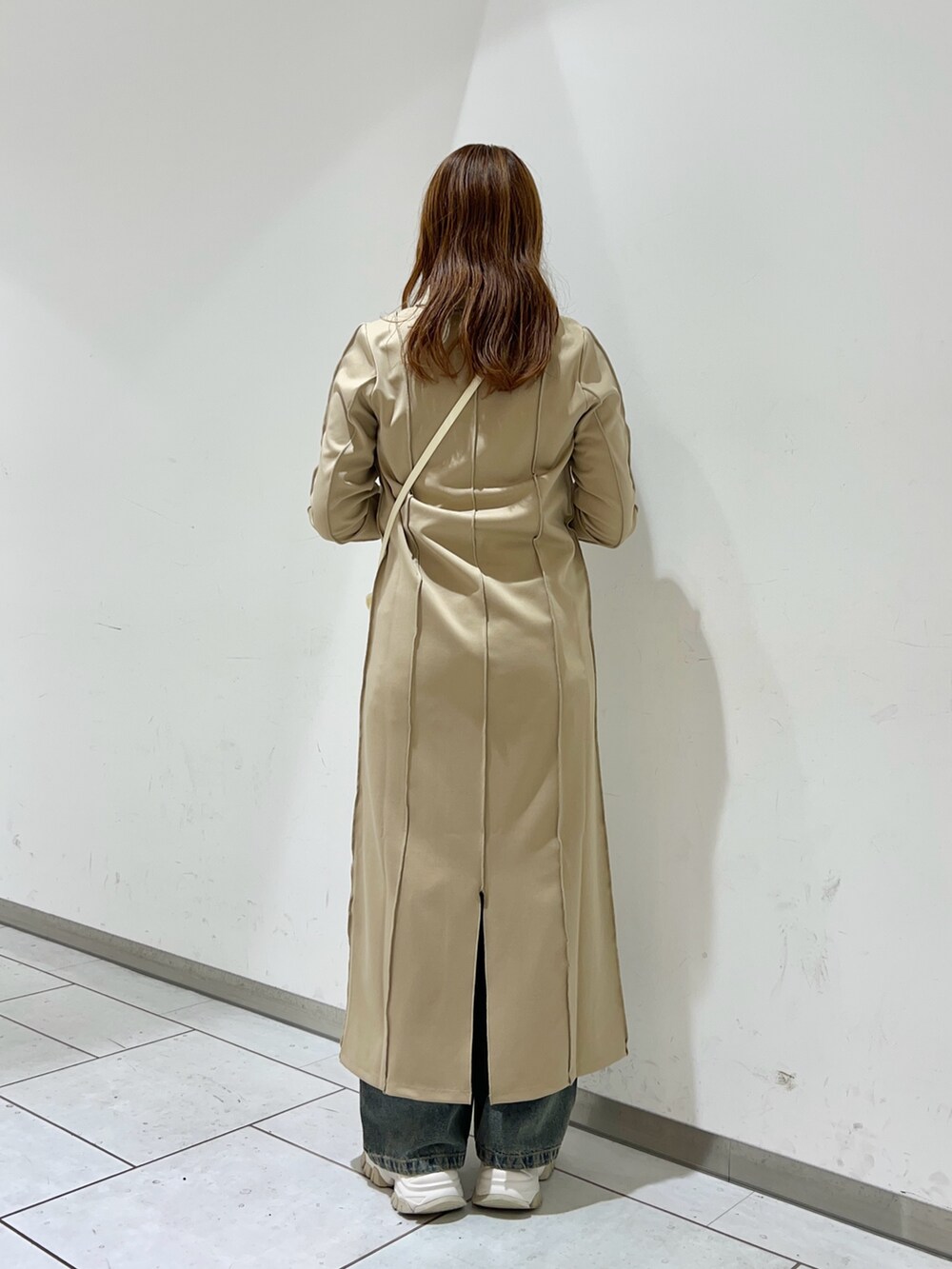 パープル系のワンピース、ブルー系のデニムパンツ、ホワイト系のショルダーバッグを着用したレディースの冬コーディネートの4枚目の写真