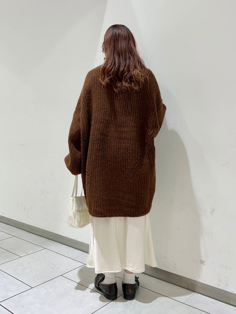 ブラウン系のワンピース、ホワイト系のスカート、ホワイト系のハンドバッグを着用したレディースの冬コーディネートの3枚目の写真