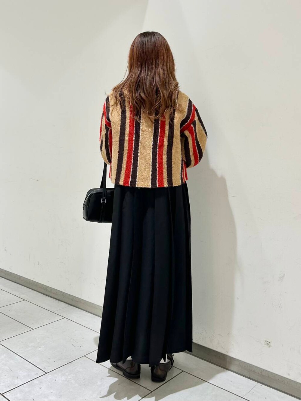 ブラック系のボストンバッグ、ベージュ系のカーディガン/ボレロ、ブラック系のローファーを着用したレディースの秋コーディネートの2枚目の写真