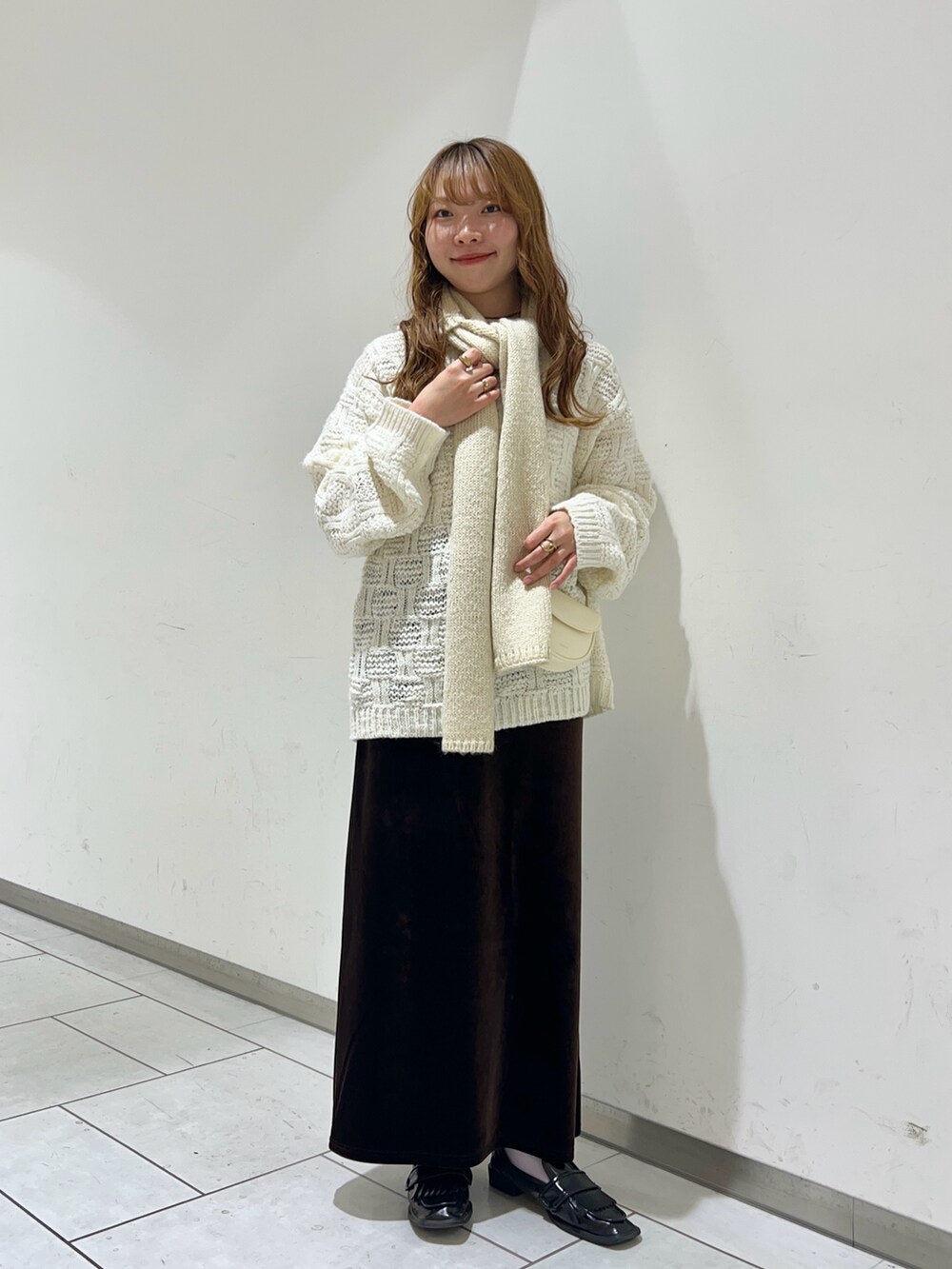 ホワイト系のニット/セーター、ホワイト系のショルダーバッグ、ブラウン系のスカートを着用したレディースの秋コーディネートの2枚目の写真