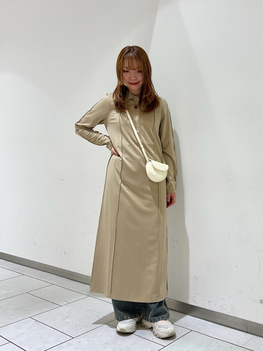 パープル系のワンピース、ブルー系のデニムパンツ、ホワイト系のショルダーバッグを着用したレディースの冬コーディネートの3枚目の写真