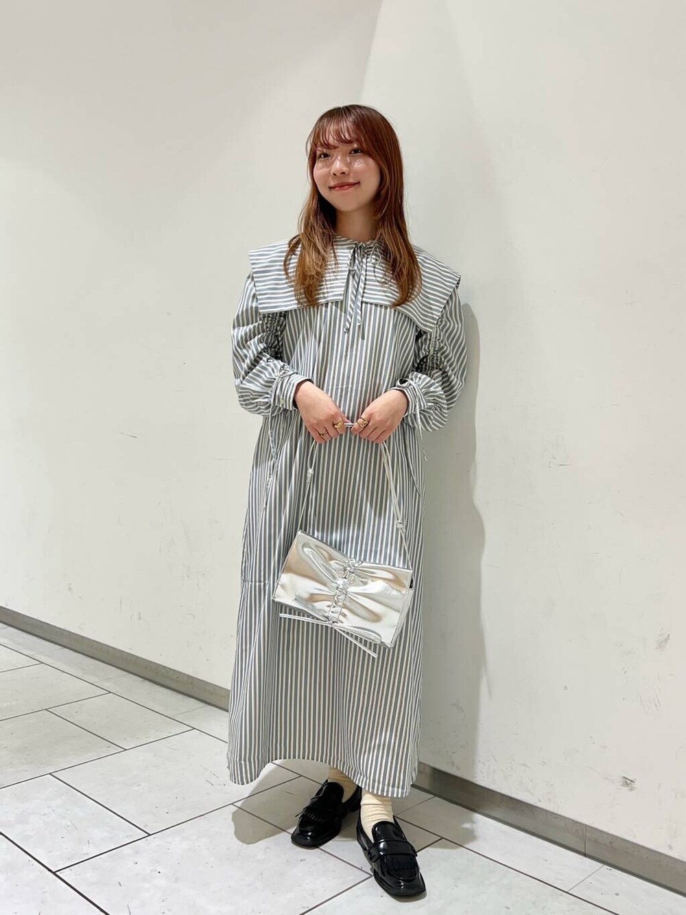 ブルー系のワンピース、シルバー系のショルダーバッグを着用したレディースの秋コーディネートの2枚目の写真