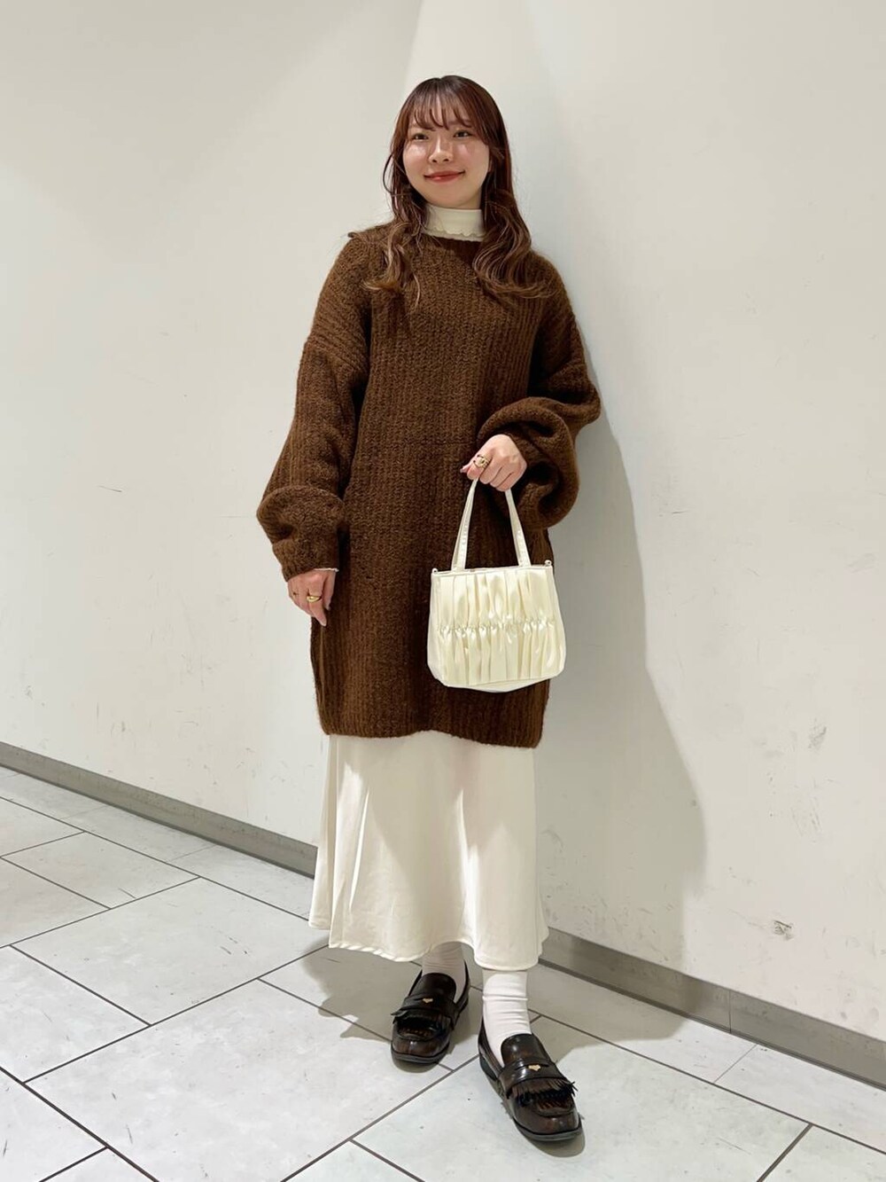 ブラウン系のワンピース、ホワイト系のスカート、ホワイト系のハンドバッグを着用したレディースの冬コーディネートの2枚目の写真