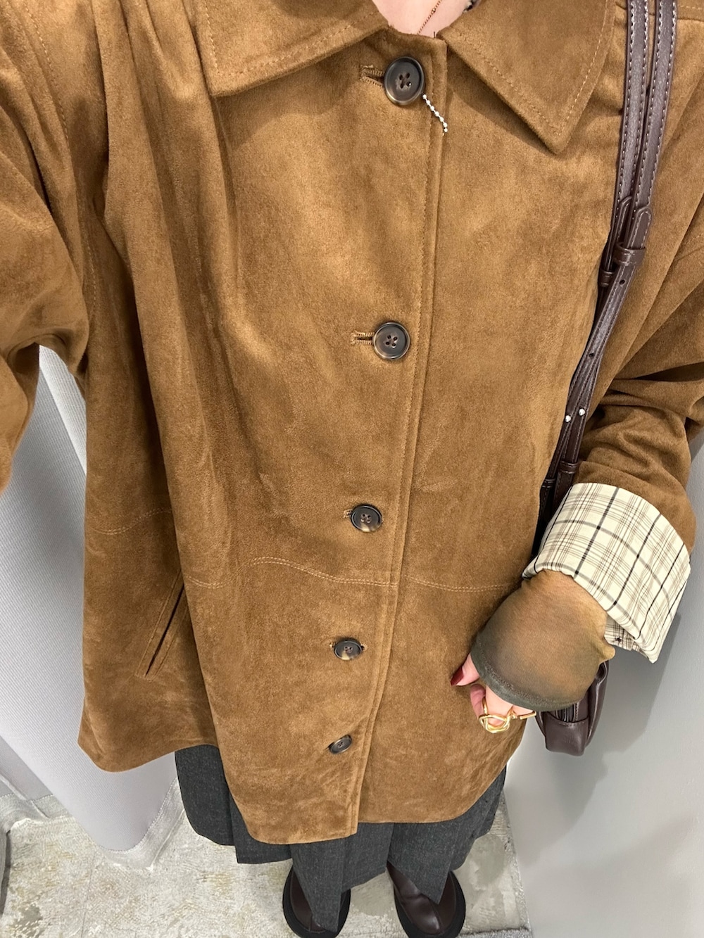 イエロー系のカバーオール、グレー系のスカート、ブラウン系のショルダーバッグを着用したレディースの秋コーディネートの4枚目の写真