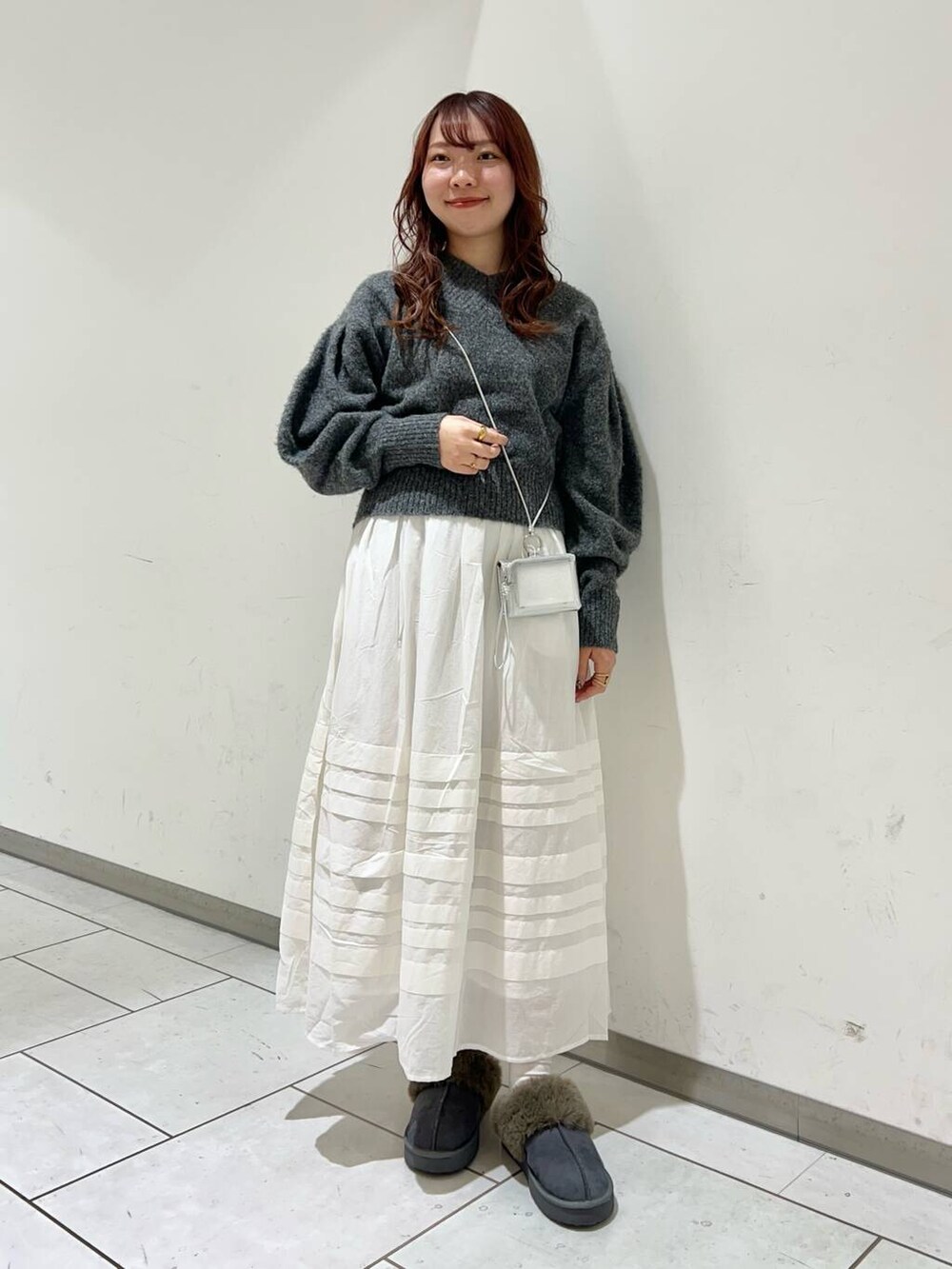 グレー系のニット/セーター、ホワイト系のスカート、グレー系のその他シューズを着用したレディースの冬コーディネートの2枚目の写真