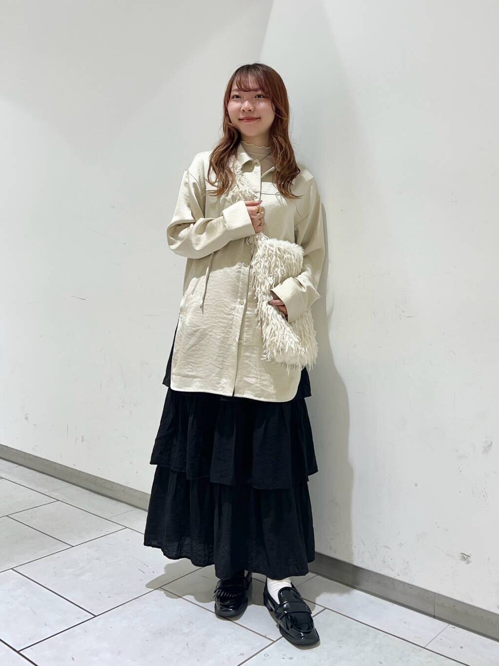 ホワイト系のショルダーバッグ、ブラック系のローファー、ベージュ系のシャツ/ブラウスを着用したレディースの冬コーディネートの2枚目の写真