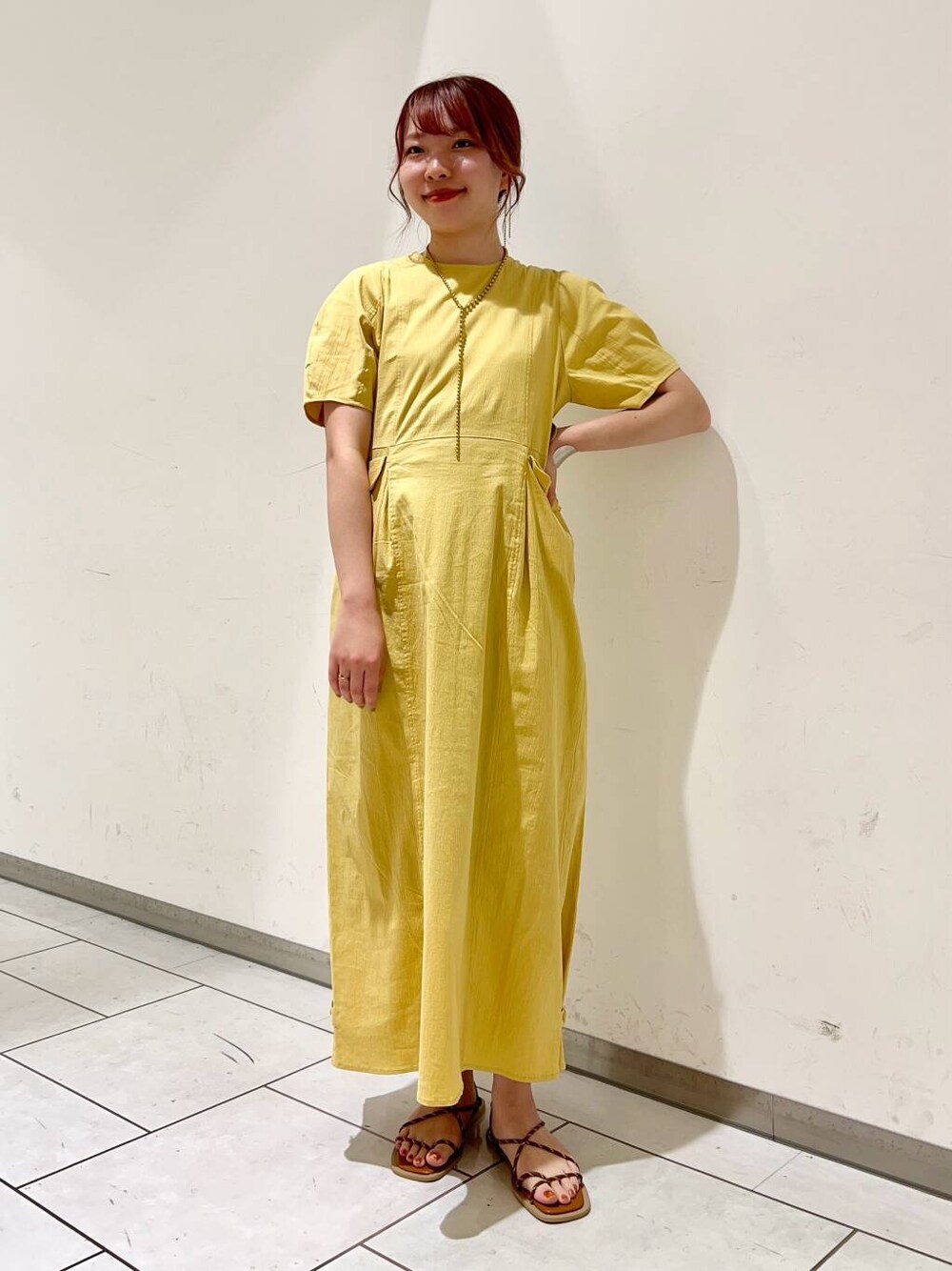 イエロー系のワンピース、ブラウン系のサンダルを着用したレディースの夏コーディネートの2枚目の写真