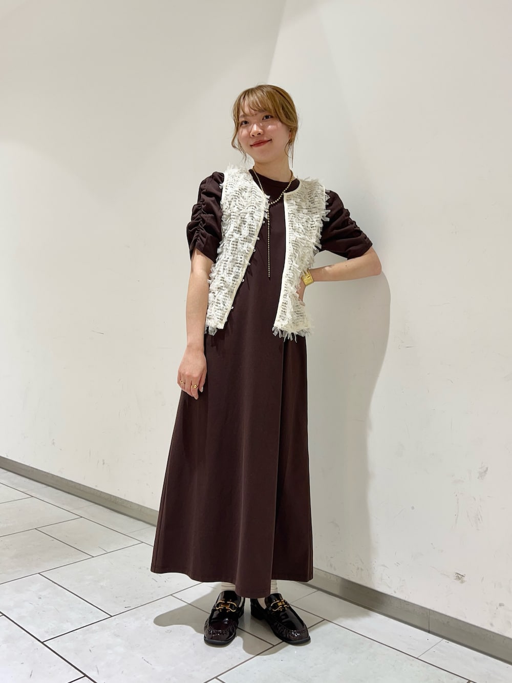 ホワイト系のベスト、ブラウン系のワンピース、ブラウン系のローファーを着用したレディースの夏コーディネートの2枚目の写真