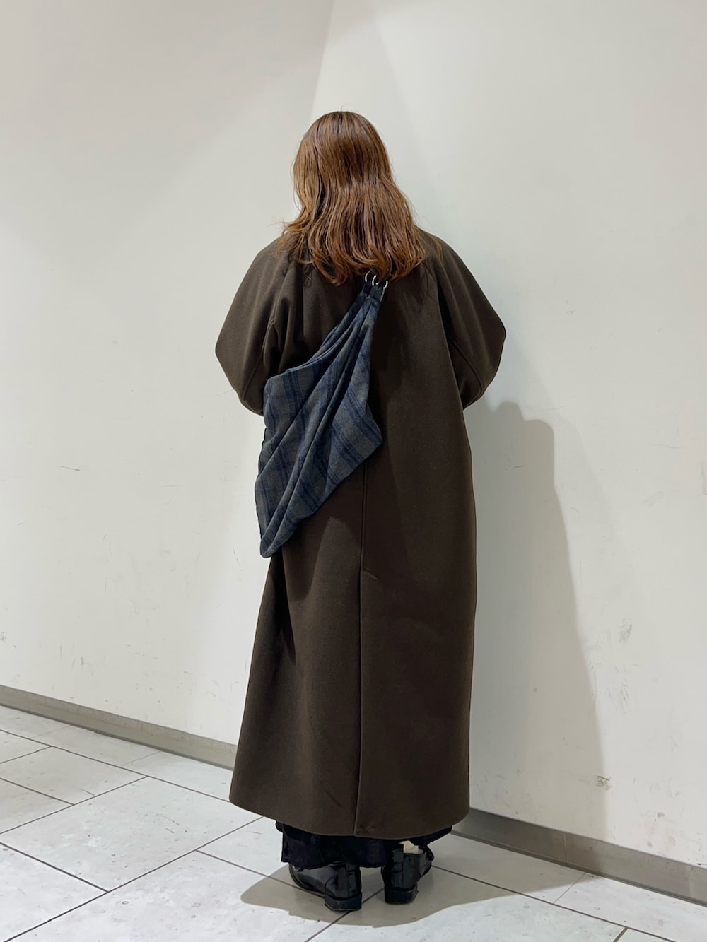 ブラウン系のステンカラーコート、グレー系のトートバッグを着用したレディースの冬コーディネートの3枚目の写真