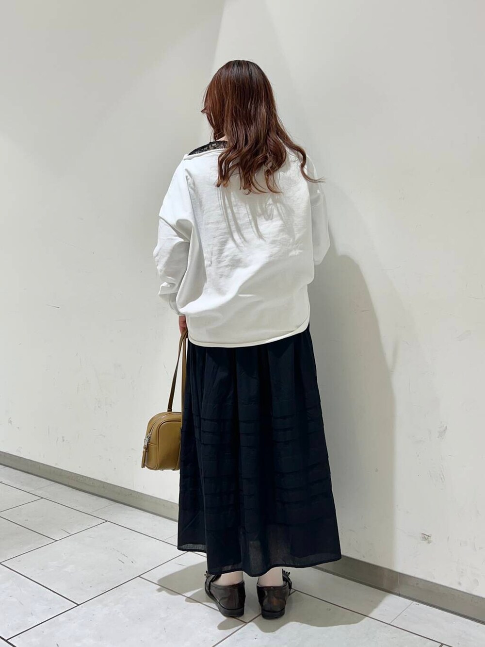グリーン系のボストンバッグ、ブラック系のスカート、ブラック系のTシャツ/カットソーを着用したレディースの冬コーディネートの2枚目の写真