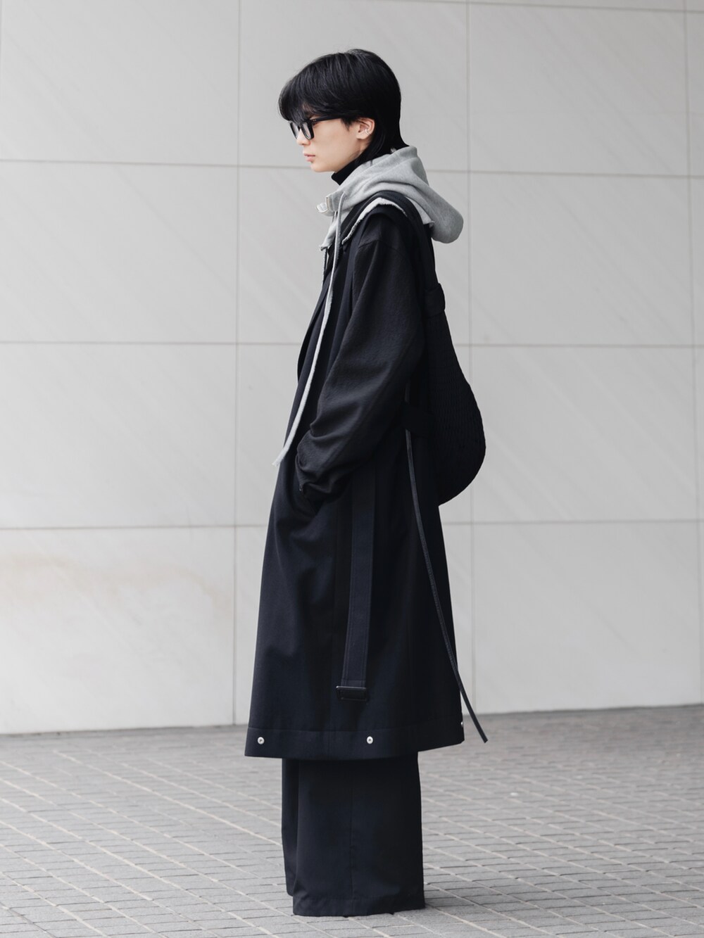 ブラック系のスラックス、ブラック系のブーツ、ブラック系のショルダーバッグを着用したメンズの冬コーディネートの2枚目の写真