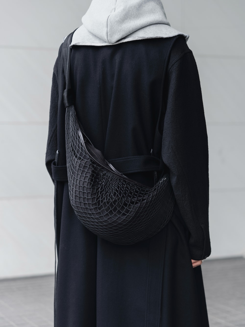 ブラック系のスラックス、ブラック系のブーツ、ブラック系のショルダーバッグを着用したメンズの冬コーディネートの3枚目の写真