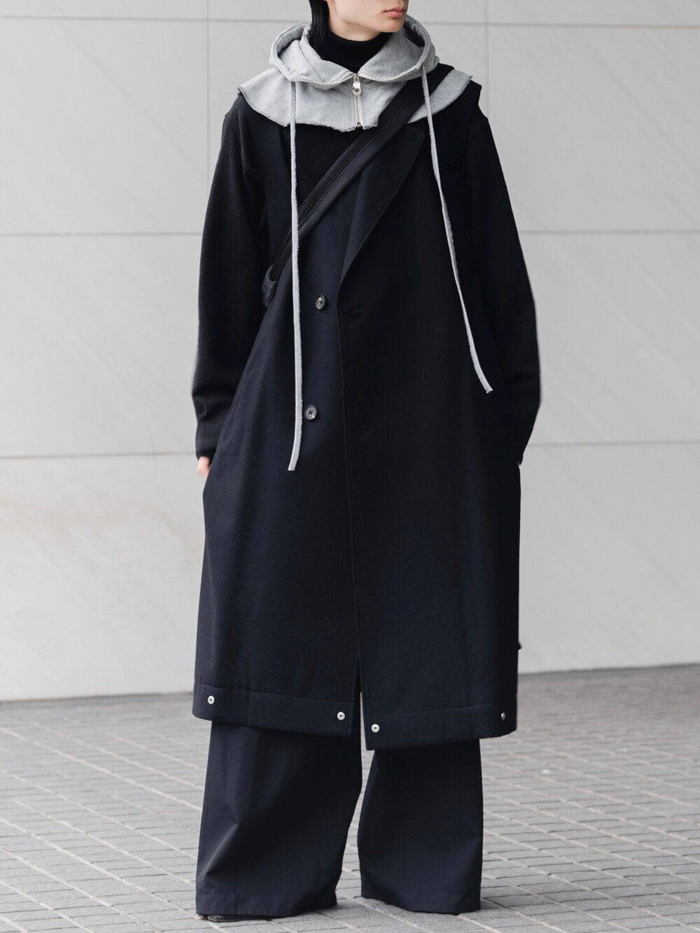 ブラック系のスラックス、ブラック系のブーツ、ブラック系のショルダーバッグを着用したメンズの冬コーディネートの4枚目の写真