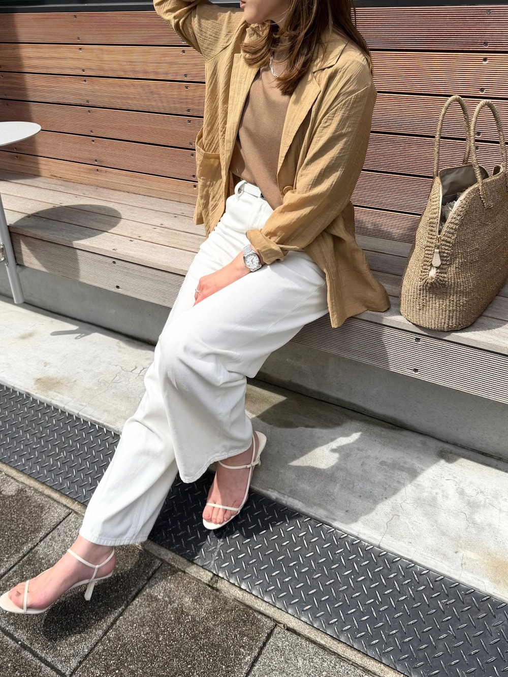 ベージュ系のテーラードジャケット、ホワイト系のデニムパンツ、ベージュ系のニット/セーターを着用したレディースの春コーディネートの3枚目の写真