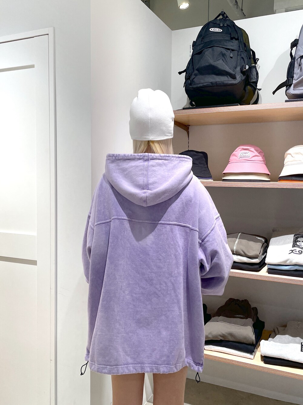 パープル系のパーカー、ホワイト系のニットキャップ/ビーニー、ブラック系のコインケースを着用したレディースの冬コーディネートの4枚目の写真