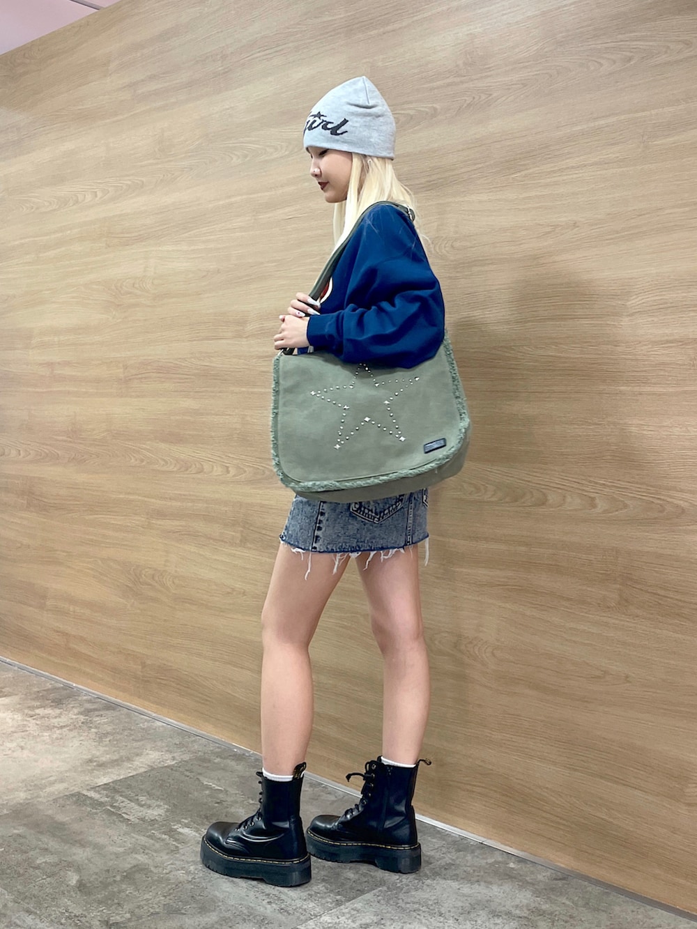 ブルー系のスウェット、グリーン系のショルダーバッグ、ブルー系のデニムスカートを着用したレディースの秋コーディネートの2枚目の写真