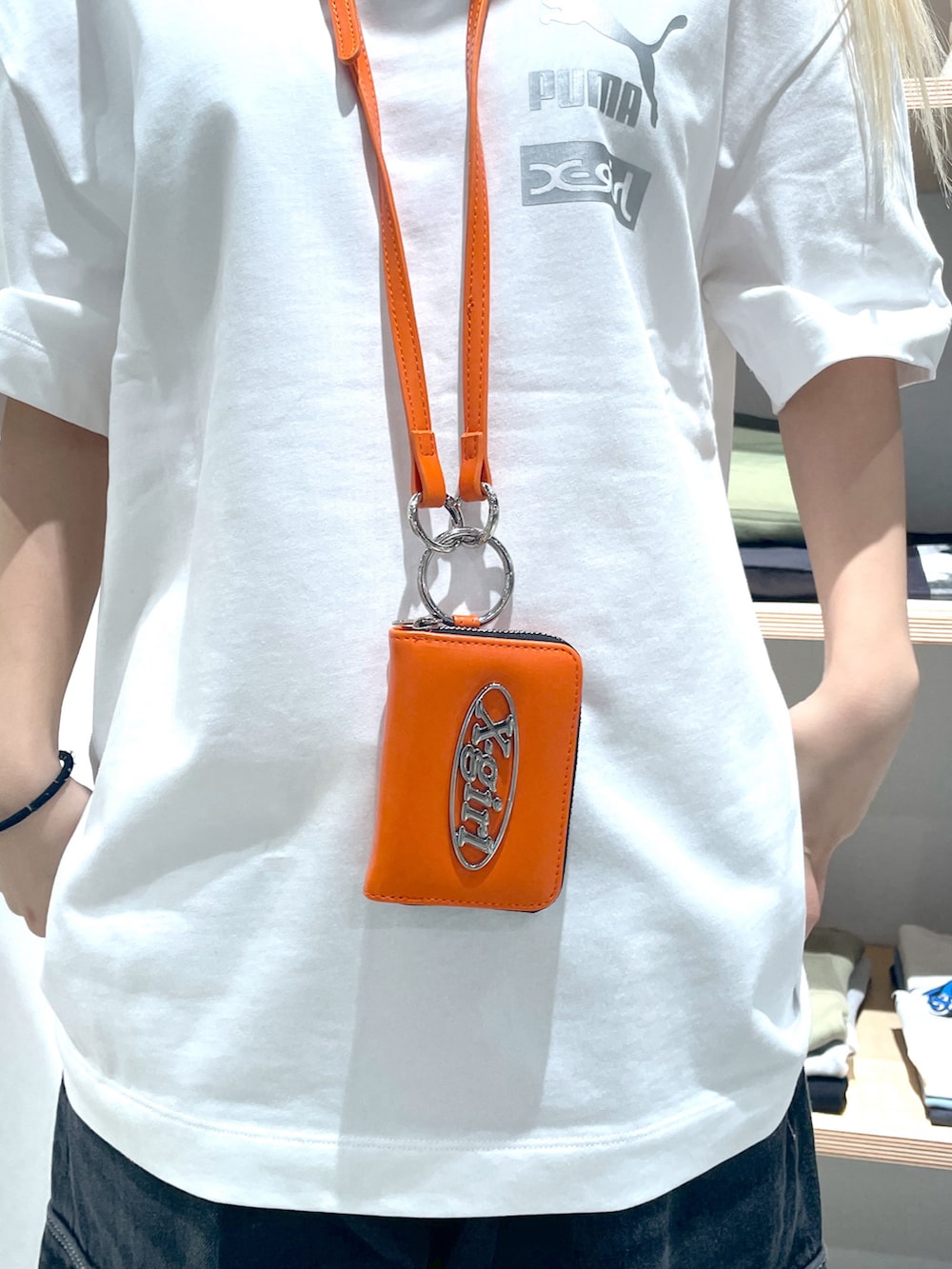 ホワイト系のTシャツ/カットソー、ブラック系のカーゴパンツ、オレンジ系のカードケースを着用したレディースの春コーディネートの5枚目の写真