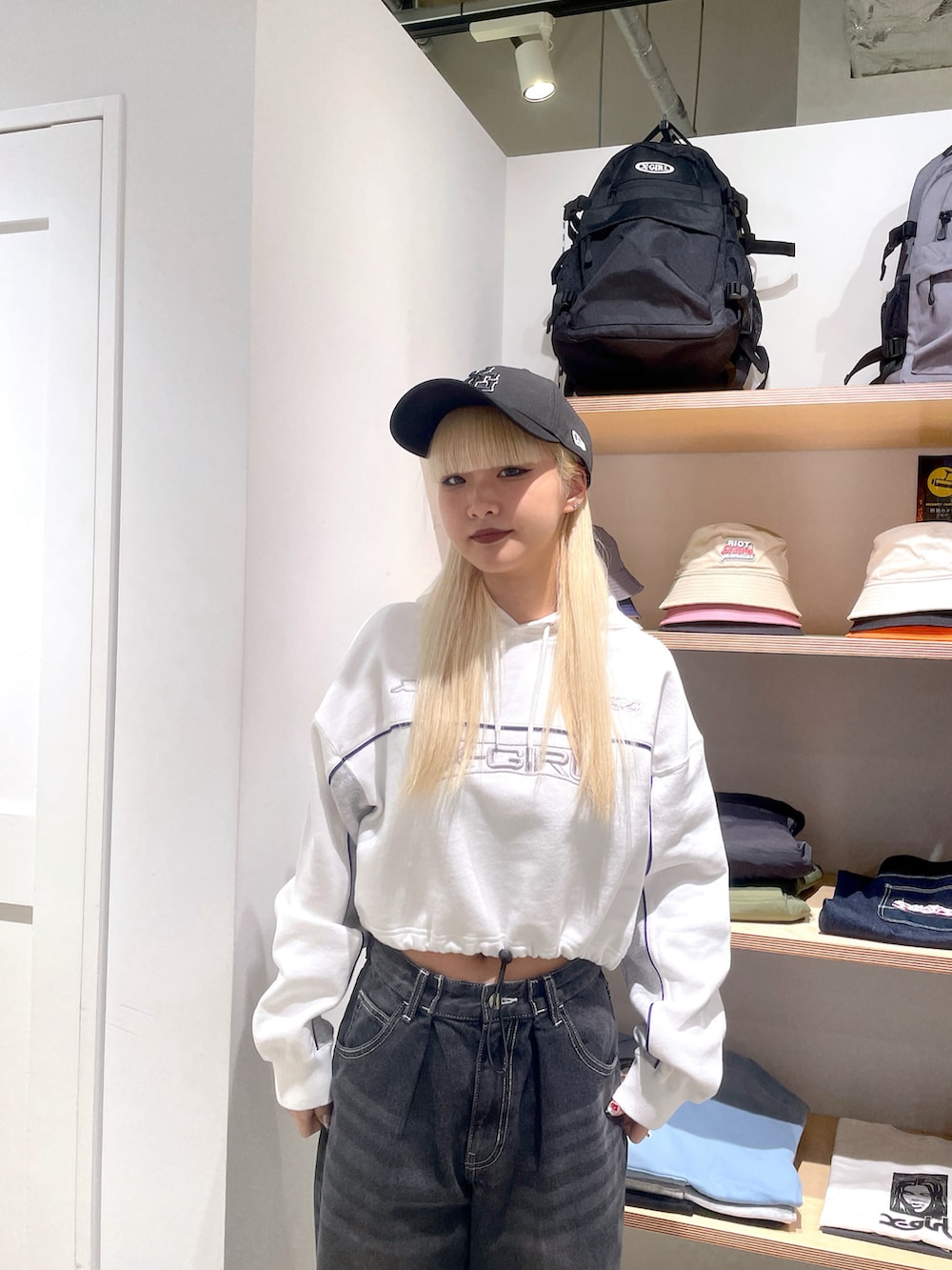 ホワイト系のパーカー、ブラック系のデニムパンツ、ブラック系のキャップを着用したレディースの冬コーディネートの4枚目の写真