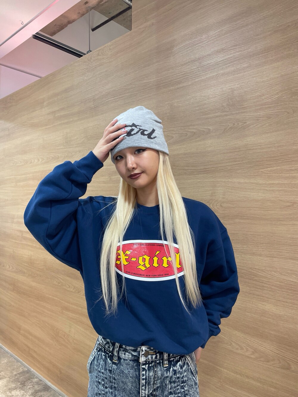 ブルー系のスウェット、グリーン系のショルダーバッグ、ブルー系のデニムスカートを着用したレディースの秋コーディネートの4枚目の写真