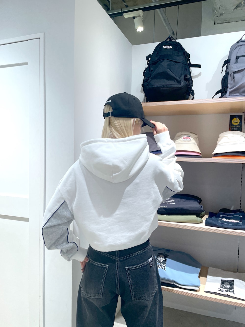 ホワイト系のパーカー、ブラック系のデニムパンツ、ブラック系のキャップを着用したレディースの冬コーディネートの5枚目の写真