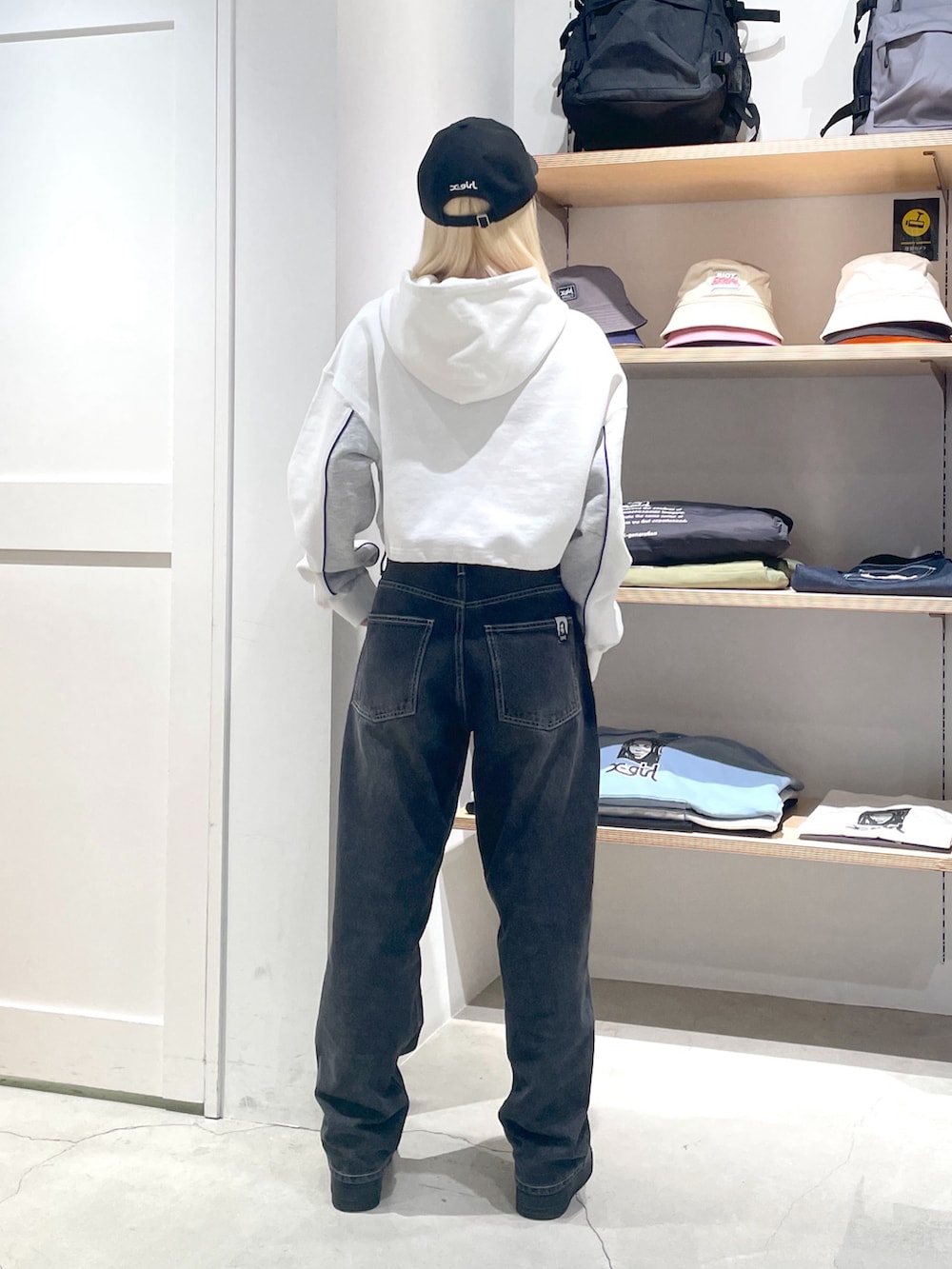 ホワイト系のパーカー、ブラック系のデニムパンツ、ブラック系のキャップを着用したレディースの冬コーディネートの3枚目の写真