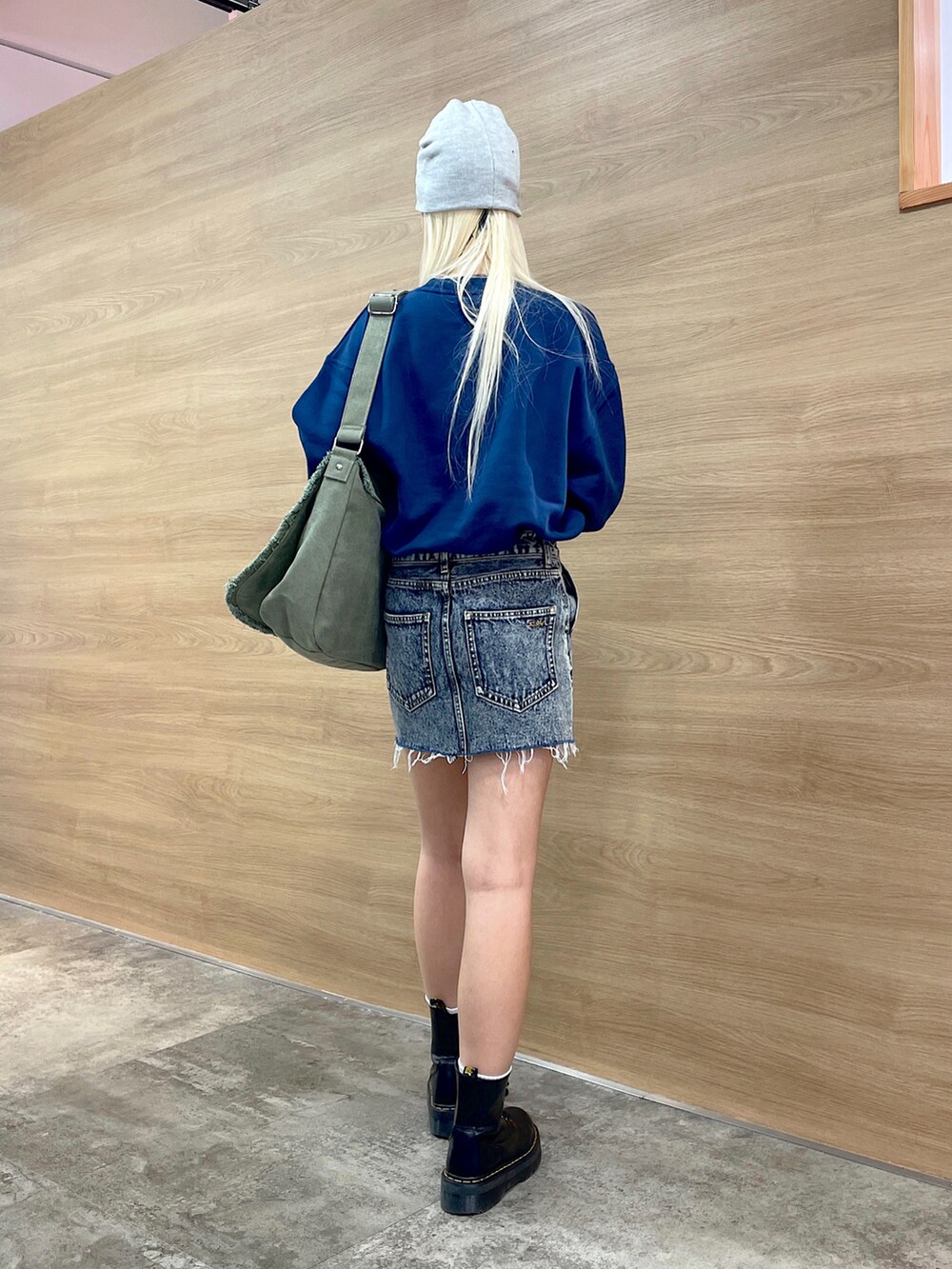 ブルー系のスウェット、グリーン系のショルダーバッグ、ブルー系のデニムスカートを着用したレディースの秋コーディネートの3枚目の写真