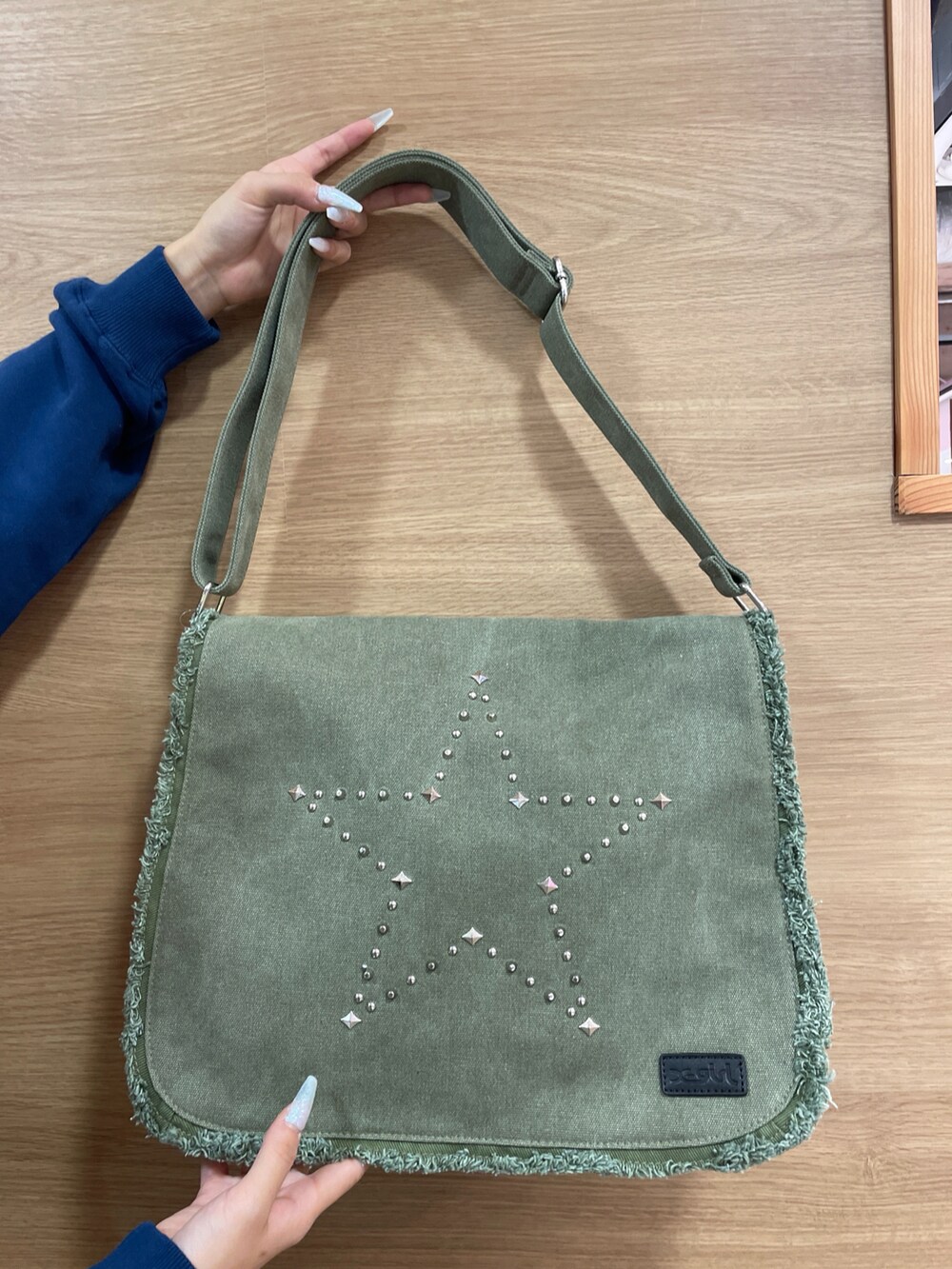 ブルー系のスウェット、グリーン系のショルダーバッグ、ブルー系のデニムスカートを着用したレディースの秋コーディネートの5枚目の写真