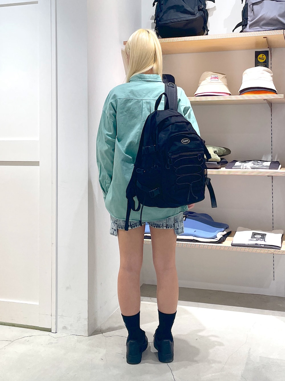 グリーン系のシャツ/ブラウス、ブラック系のバックパック/リュック、ブルー系のデニムパンツを着用したレディースの春コーディネートの3枚目の写真