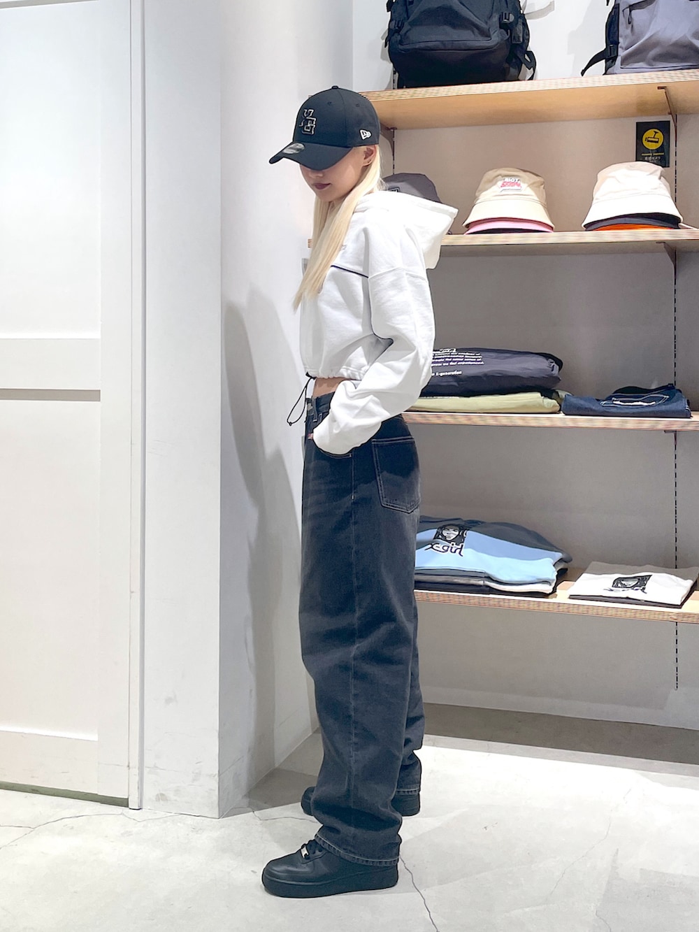 ホワイト系のパーカー、ブラック系のデニムパンツ、ブラック系のキャップを着用したレディースの冬コーディネートの2枚目の写真