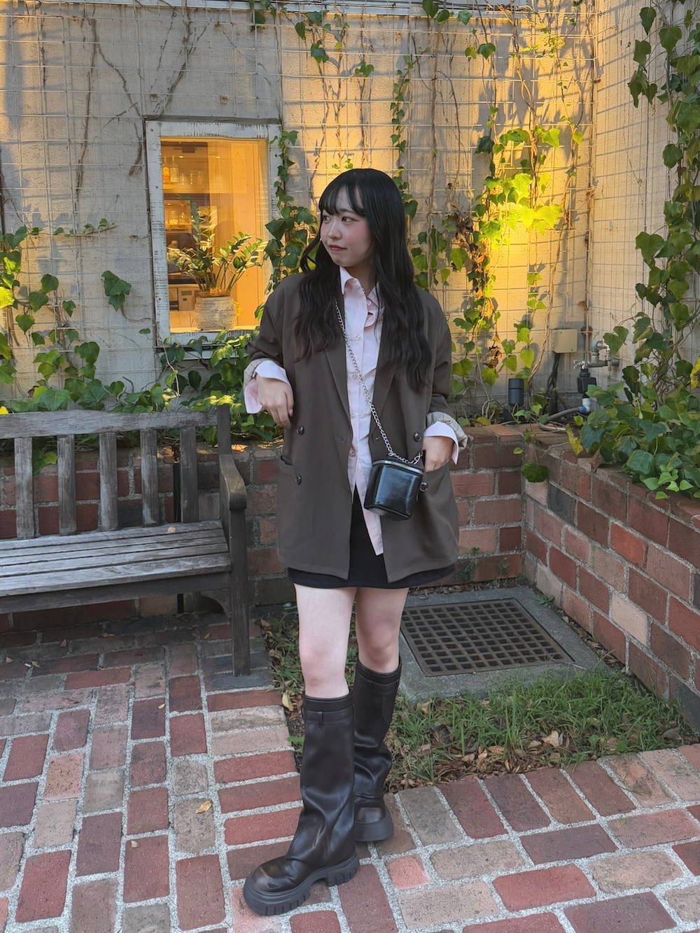 ブラウン系のテーラードジャケット、ブラック系のショルダーバッグ、ブラウン系のブーツを着用したレディースの秋コーディネートの4枚目の写真