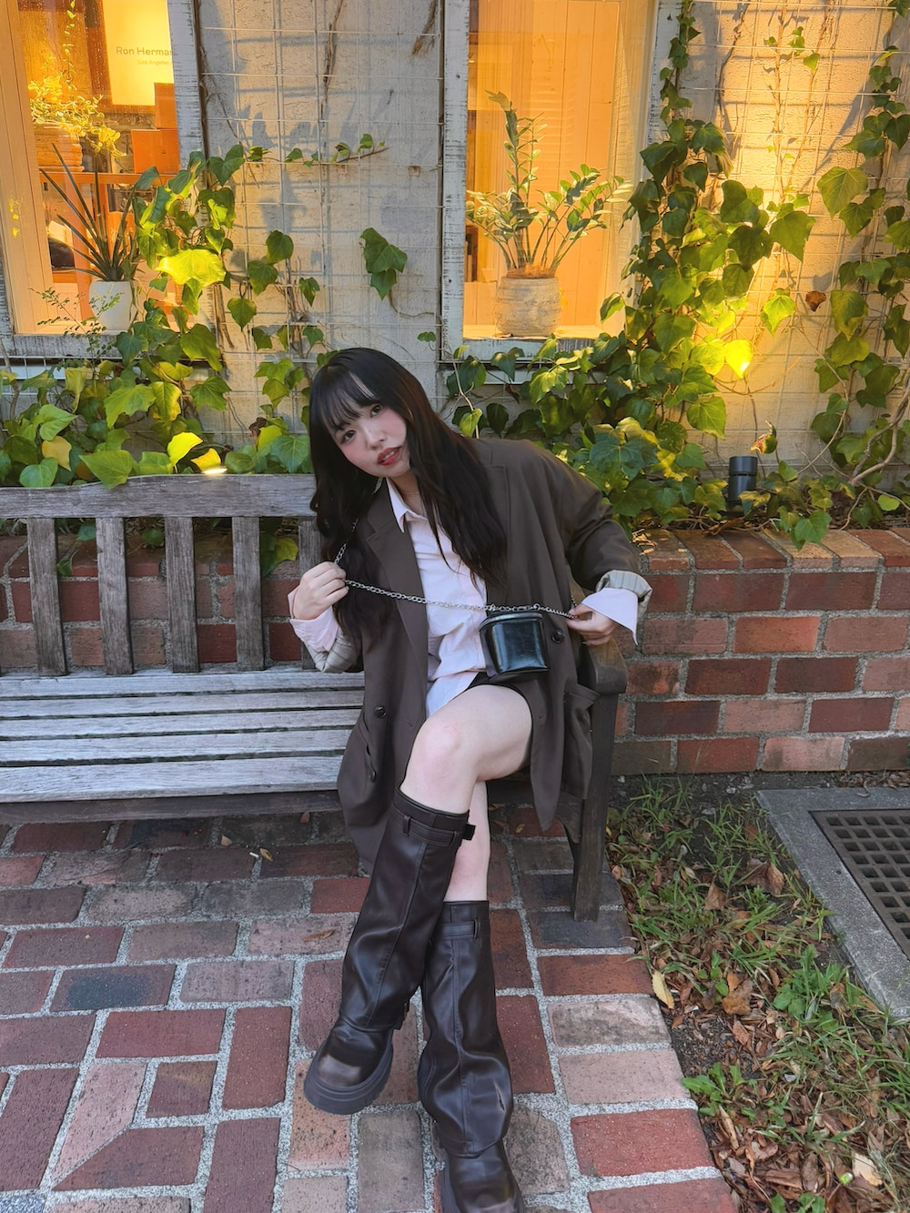 ブラウン系のテーラードジャケット、ブラック系のショルダーバッグ、ブラウン系のブーツを着用したレディースの秋コーディネートの2枚目の写真