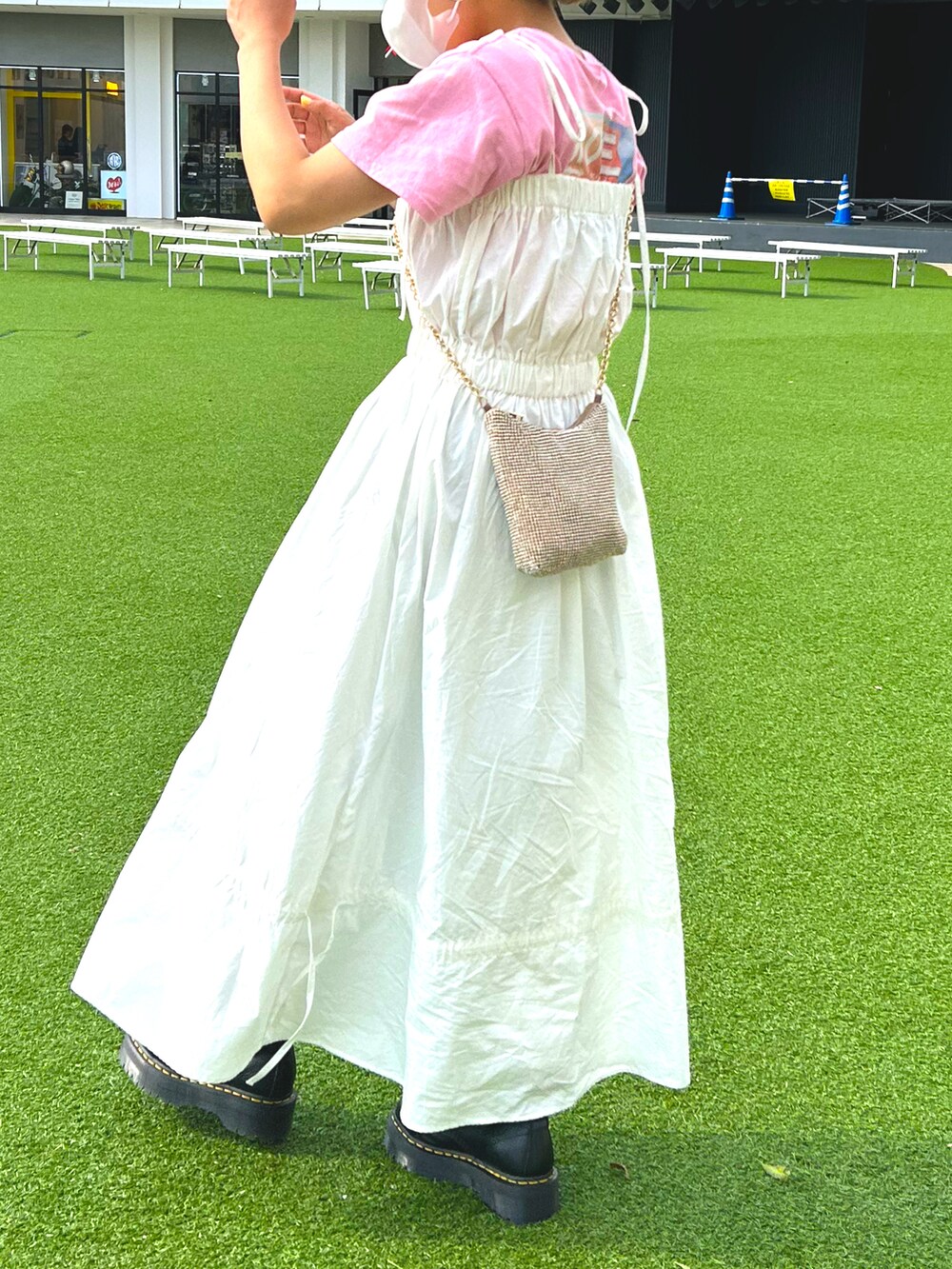 ホワイト系のワンピース、ゴールド系のショルダーバッグ、ブラック系のブーツを着用したレディースの夏コーディネートの2枚目の写真