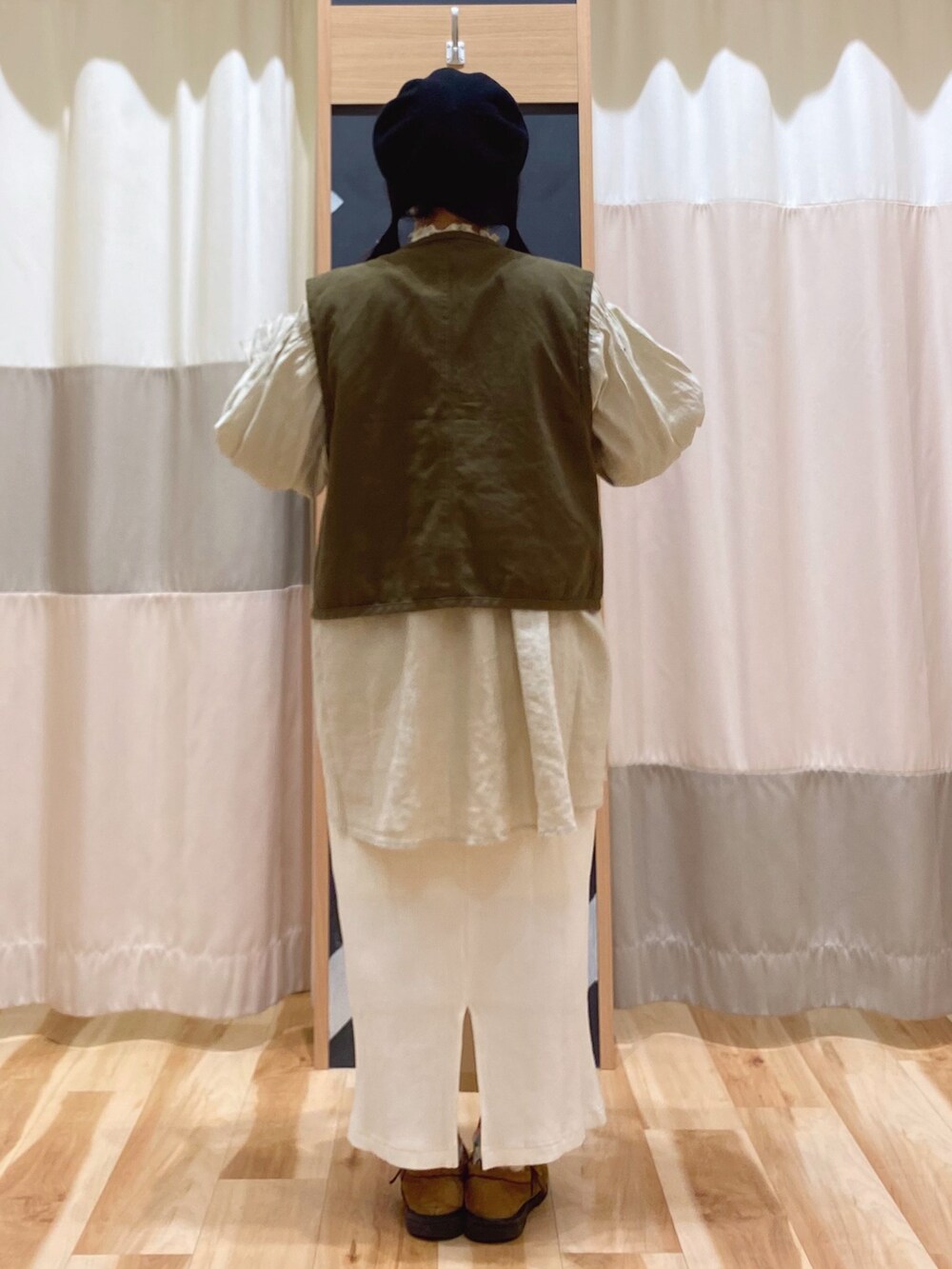 イエロー系のチュニック、グリーン系のベスト、ホワイト系のスカートを着用したレディースの春コーディネートの5枚目の写真