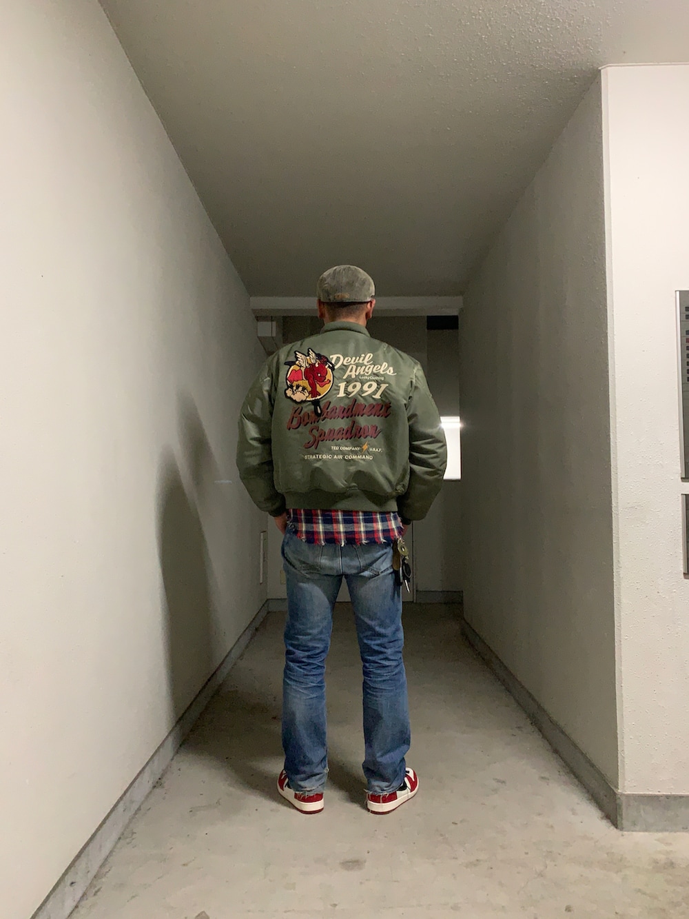 ブルー系のデニムパンツ、レッド系のスニーカー、レッド系のシャツ/ブラウスを着用したメンズの冬コーディネートの2枚目の写真