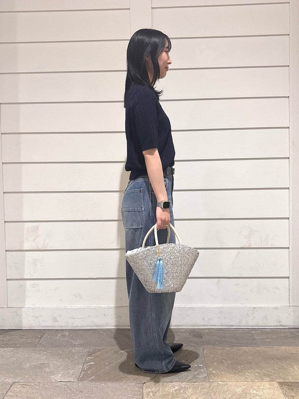 ブルー系のデニムパンツ、シルバー系のかごバッグ、ブルー系のニット/セーターを着用したレディースの春コーディネートの2枚目の写真