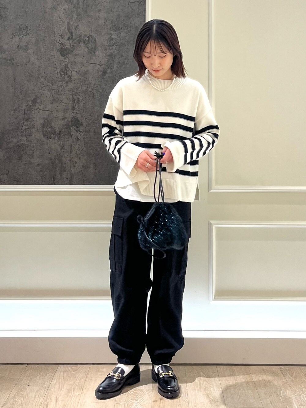 ホワイト系のニット/セーター、ブラック系のカーゴパンツ、ブラック系のローファーを着用したレディースの冬コーディネートの2枚目の写真
