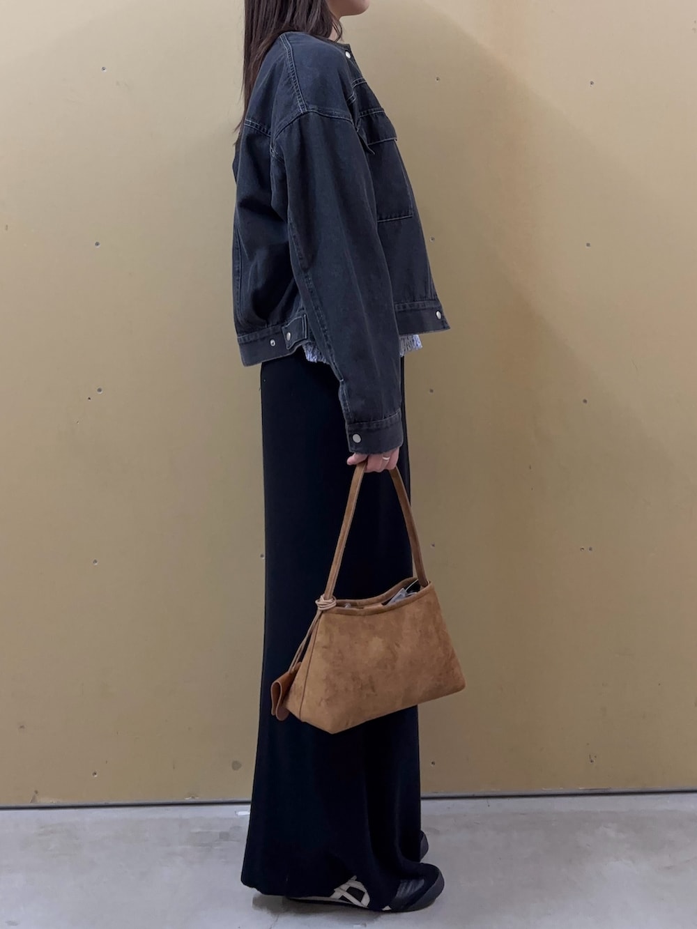 イエロー系のショルダーバッグ、ブラック系のノーカラージャケット、ブルー系のニット/セーターを着用したレディースの春コーディネートの2枚目の写真