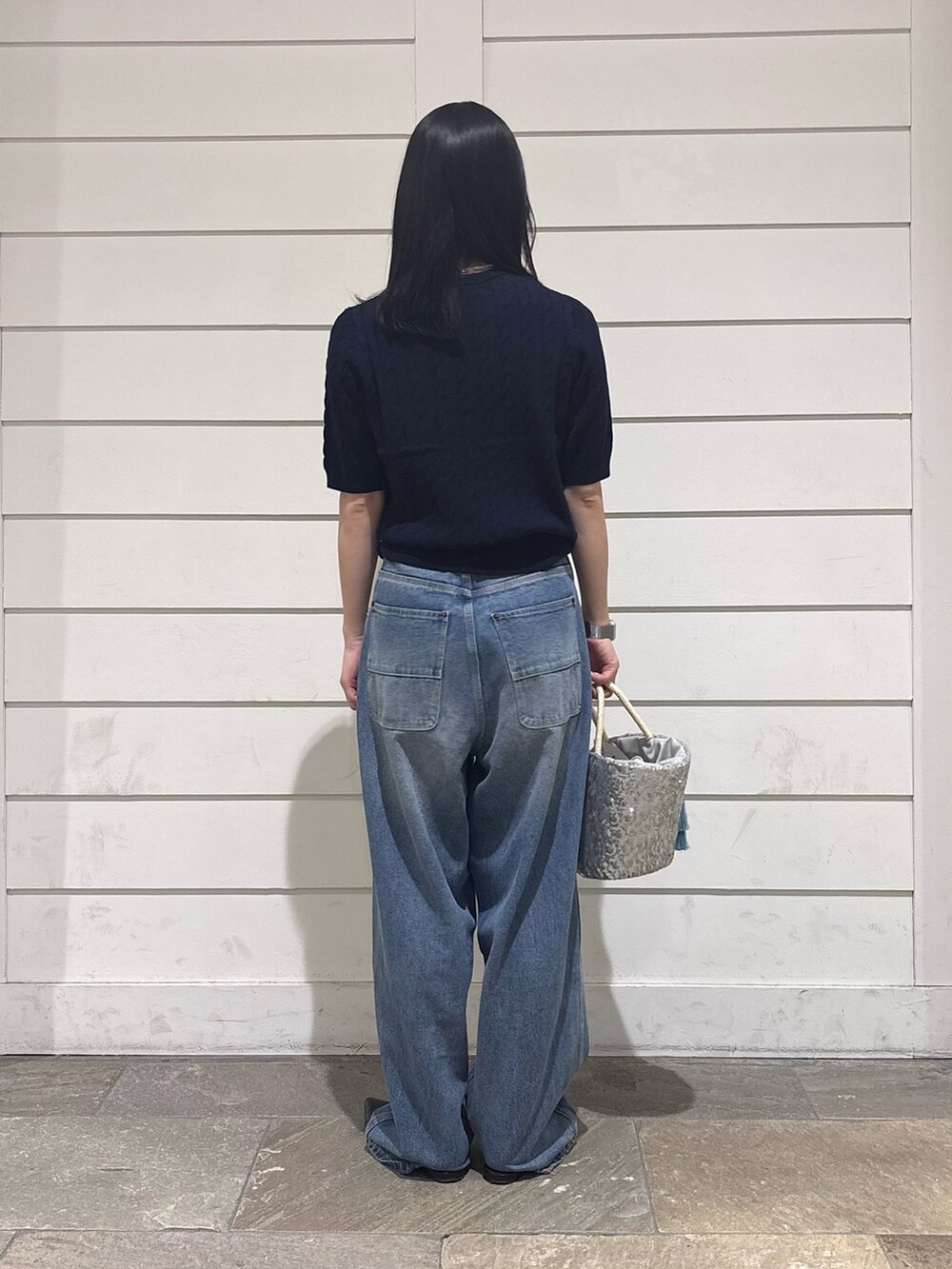 ブルー系のデニムパンツ、シルバー系のかごバッグ、ブルー系のニット/セーターを着用したレディースの春コーディネートの3枚目の写真