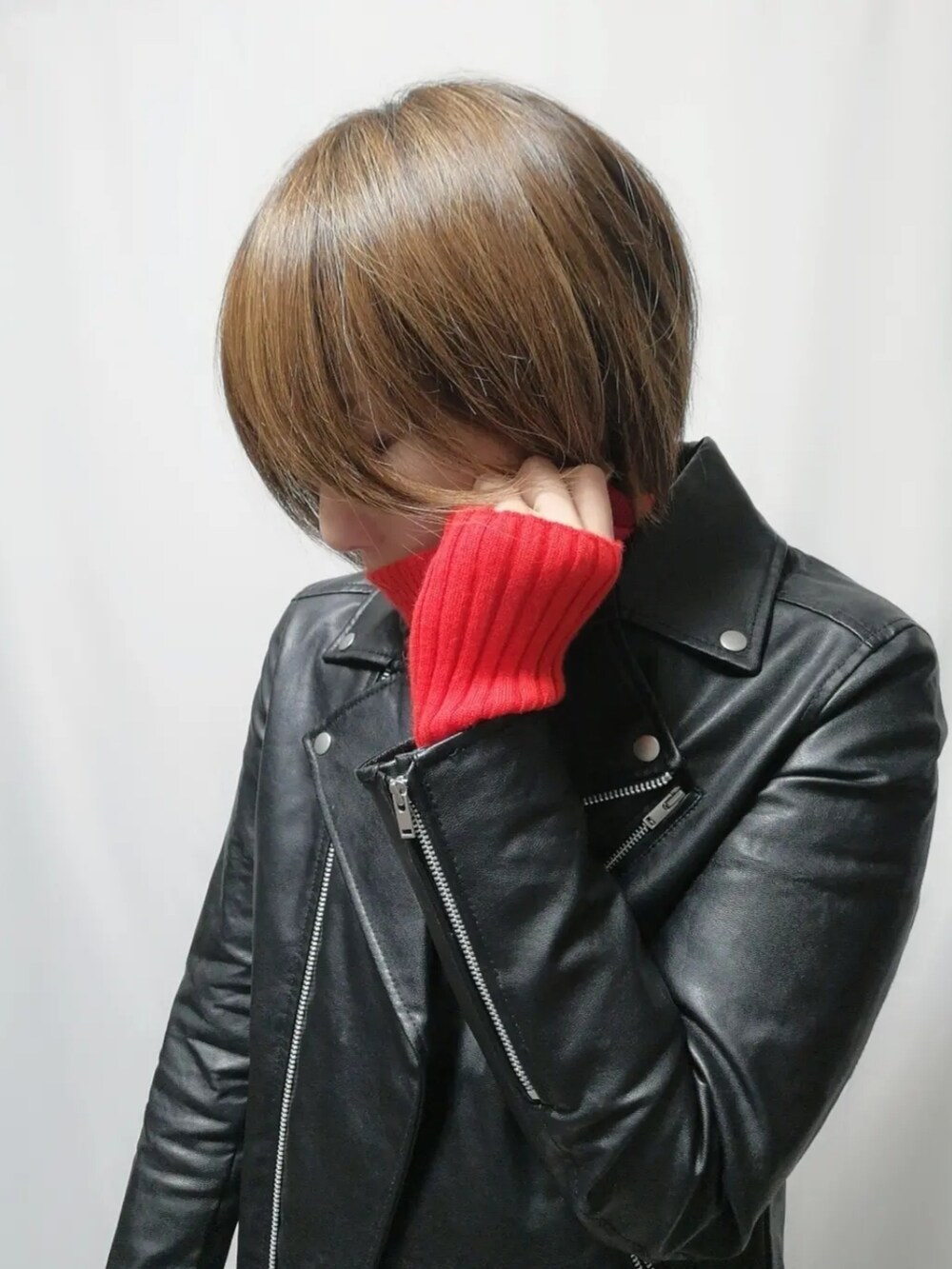 ブラック系のライダースジャケット、レッド系のニット/セーターを着用したレディースの冬コーディネートの2枚目の写真