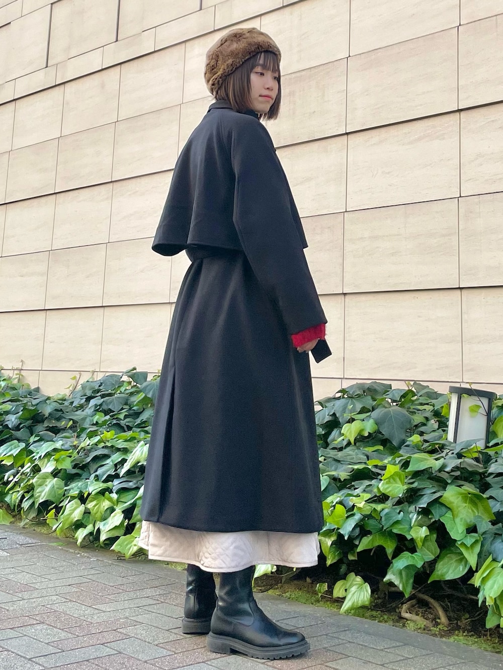 ブラック系のその他アウター、レッド系のニット/セーター、ベージュ系のスカートを着用したレディースの冬コーディネートの3枚目の写真