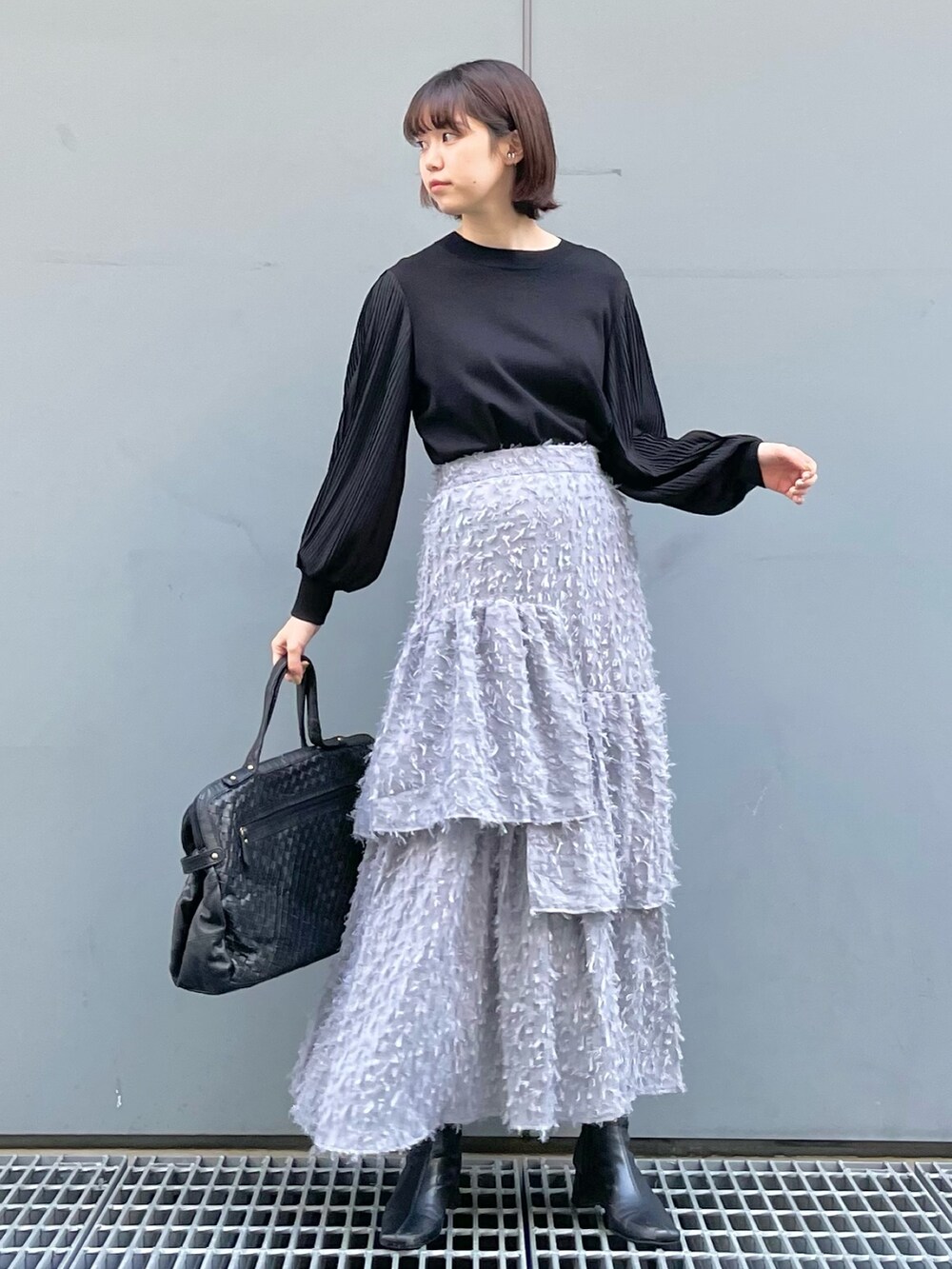 ブラック系のニット/セーター、ブラック系のショルダーバッグ、グレー系のスカートを着用したレディースの秋コーディネートの3枚目の写真